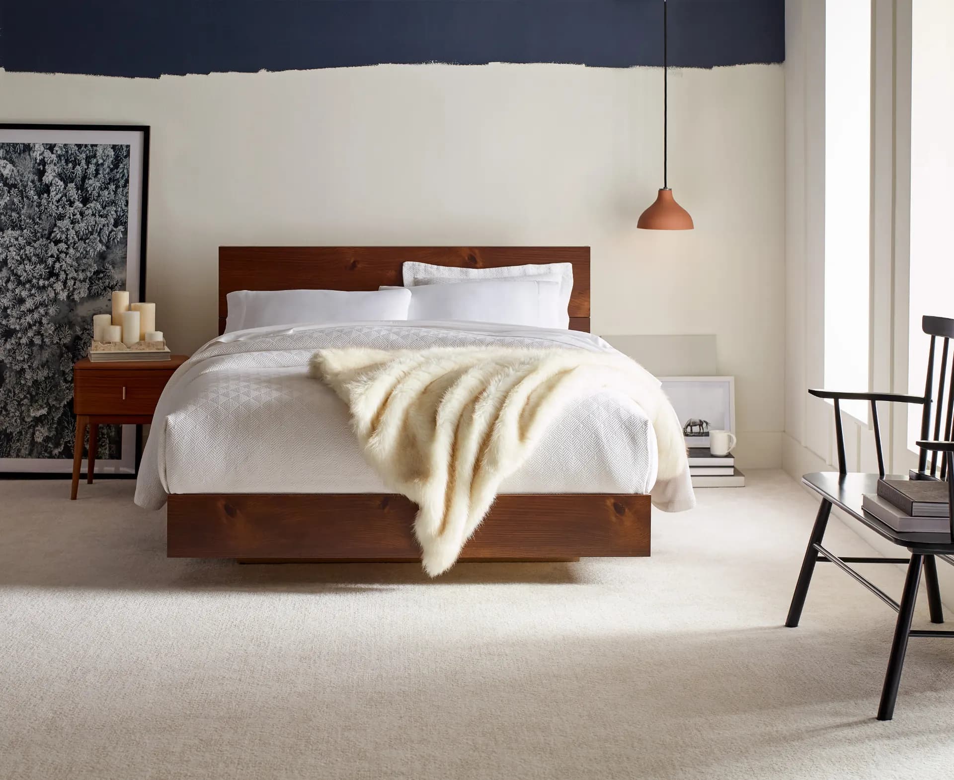 Cream cut pile carpet in a bedroom with a low wood platform bed and a hanging copper lamp