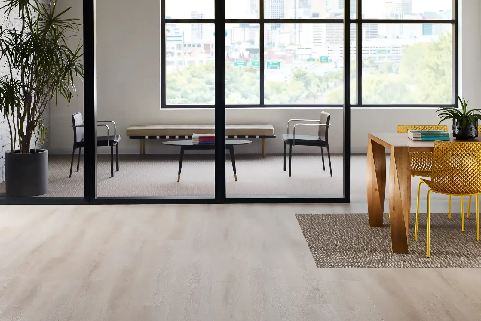 Office lounge and dining area with carpet and wood-look LVT, city view behind