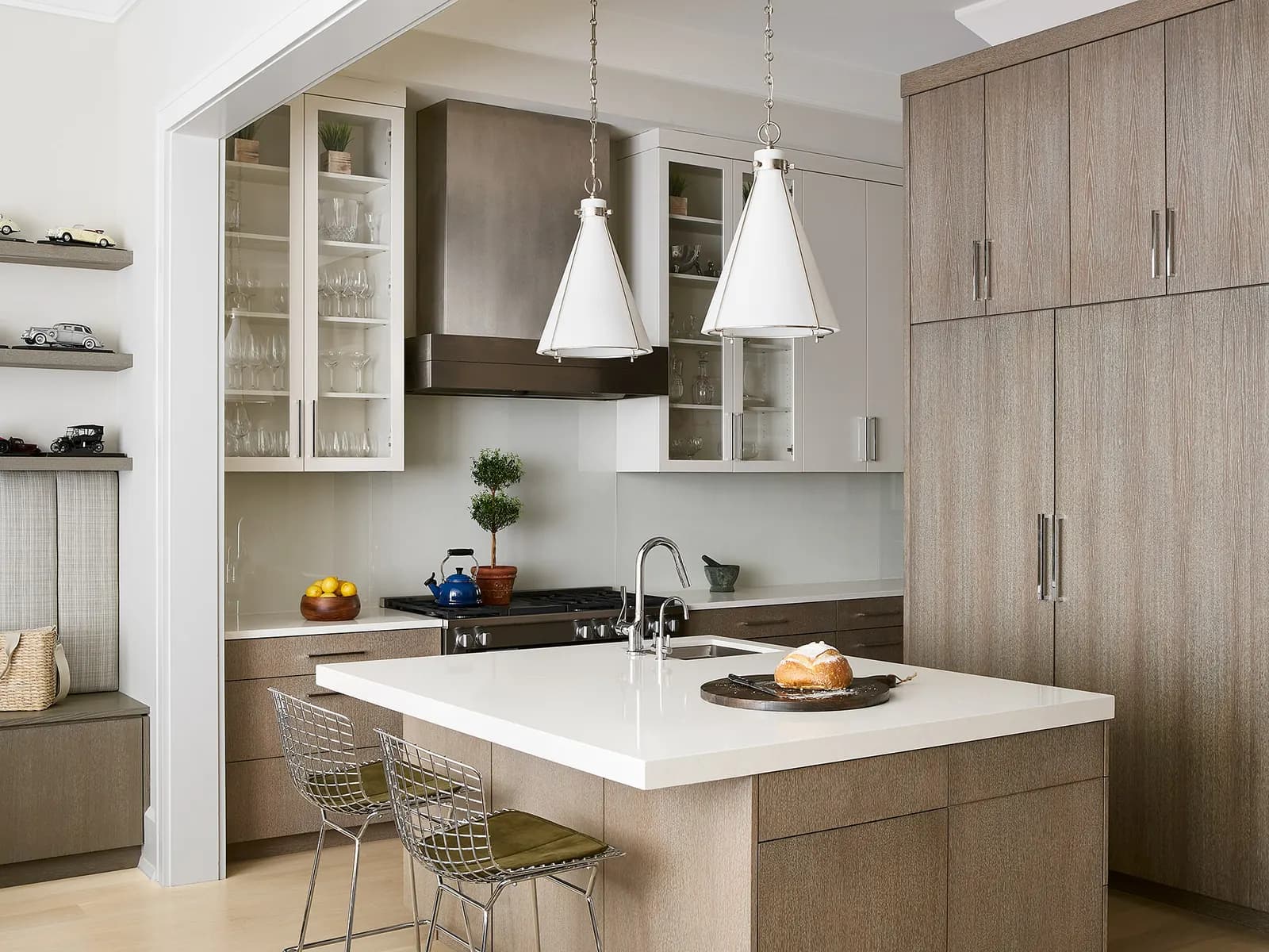 White quartz countertops beside a gas range with a blue kettle, and bread on a wooden board on the island