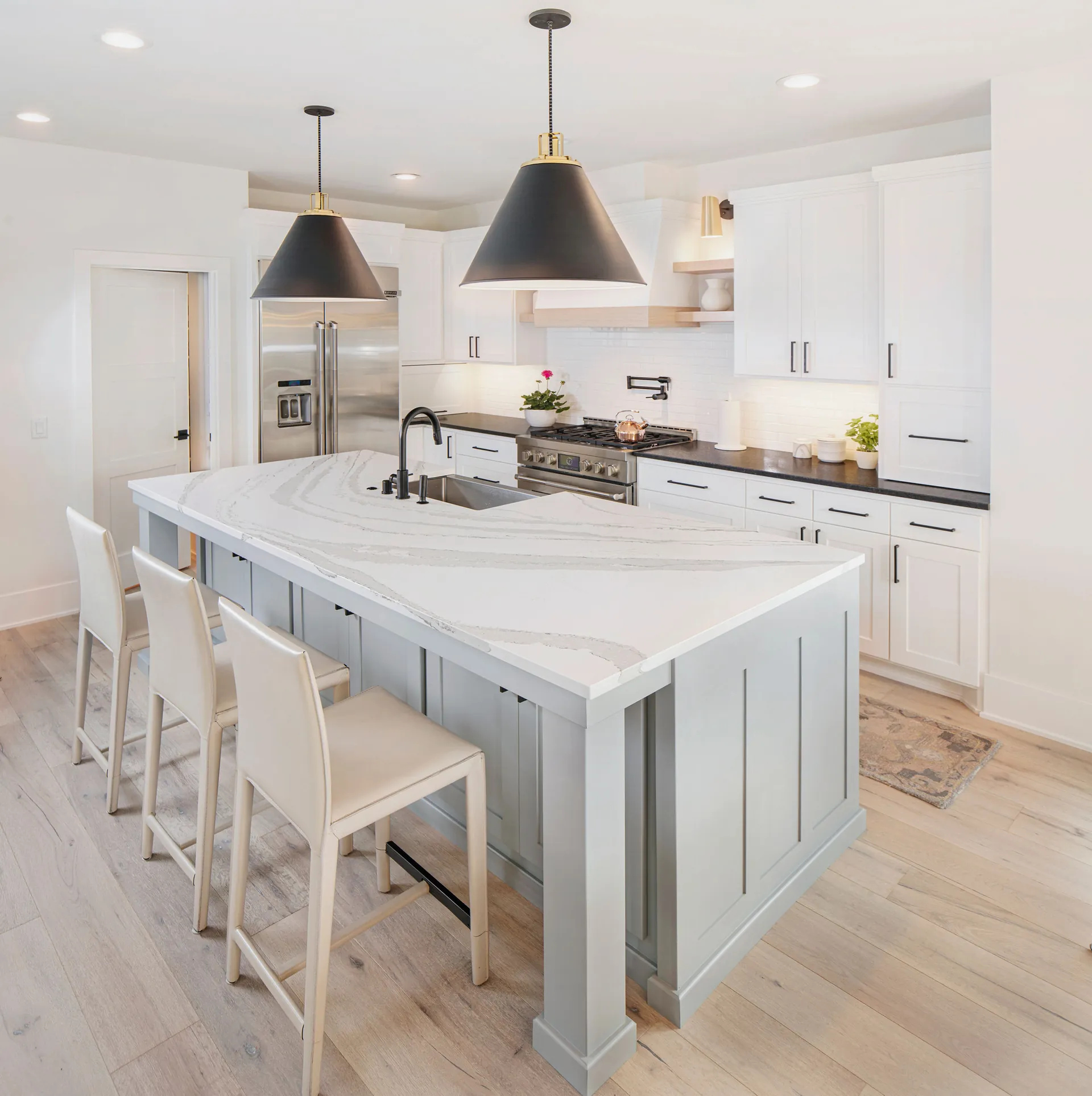 A kitchen island with a quartz countertop overhang and bar stools, from the Cambria quartz line we carry