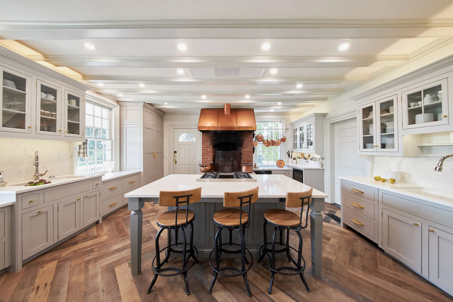 A white kitchen with a quartz island and a brick hearth, from the Cambria quartz line we carry