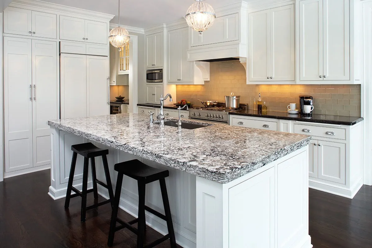 A kitchen island with a veined quartz countertop and bar stools, from the Cambria quartz line we carry