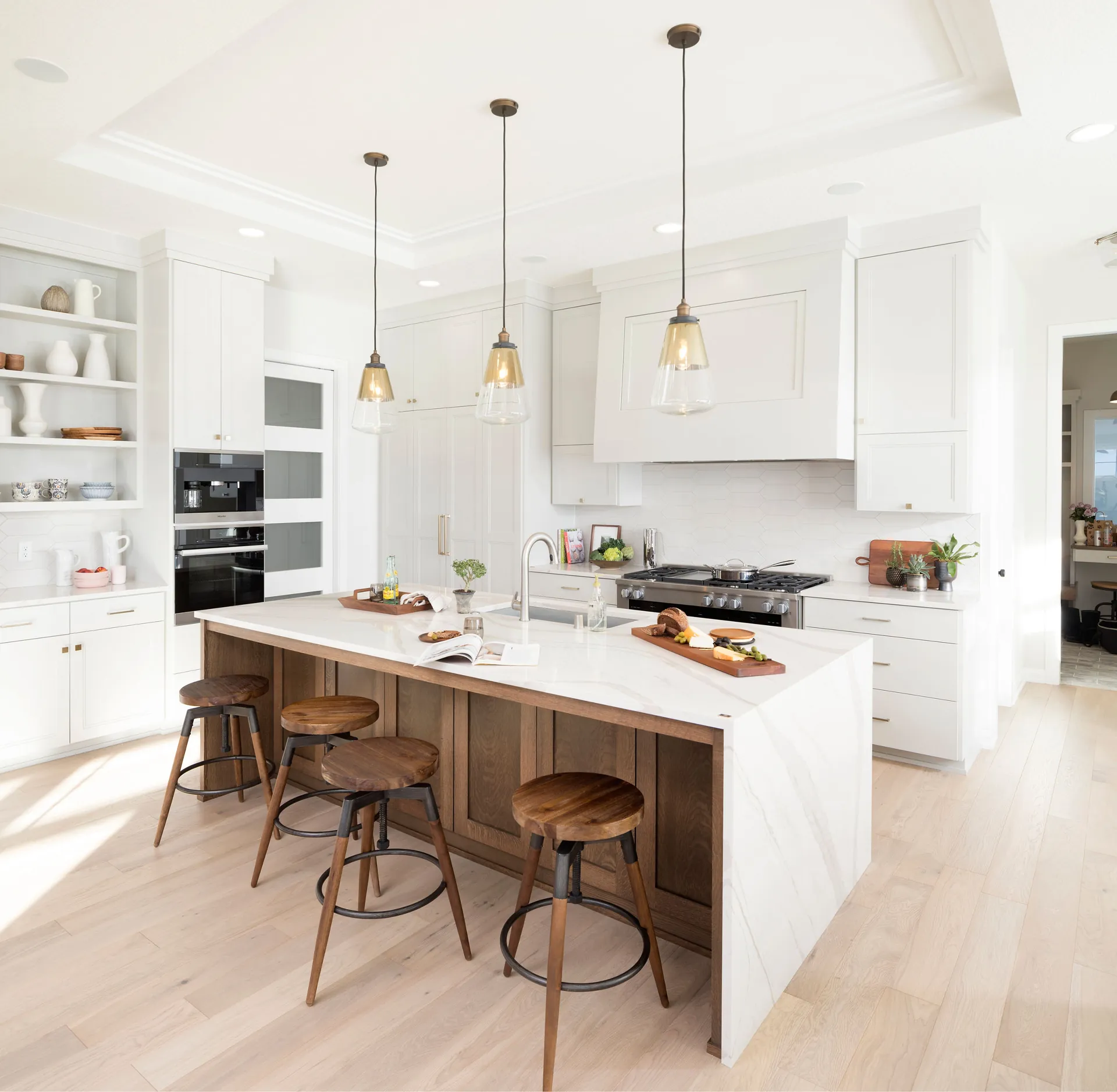 A white kitchen with a quartz island and bar stools, from the Cambria quartz line we carry