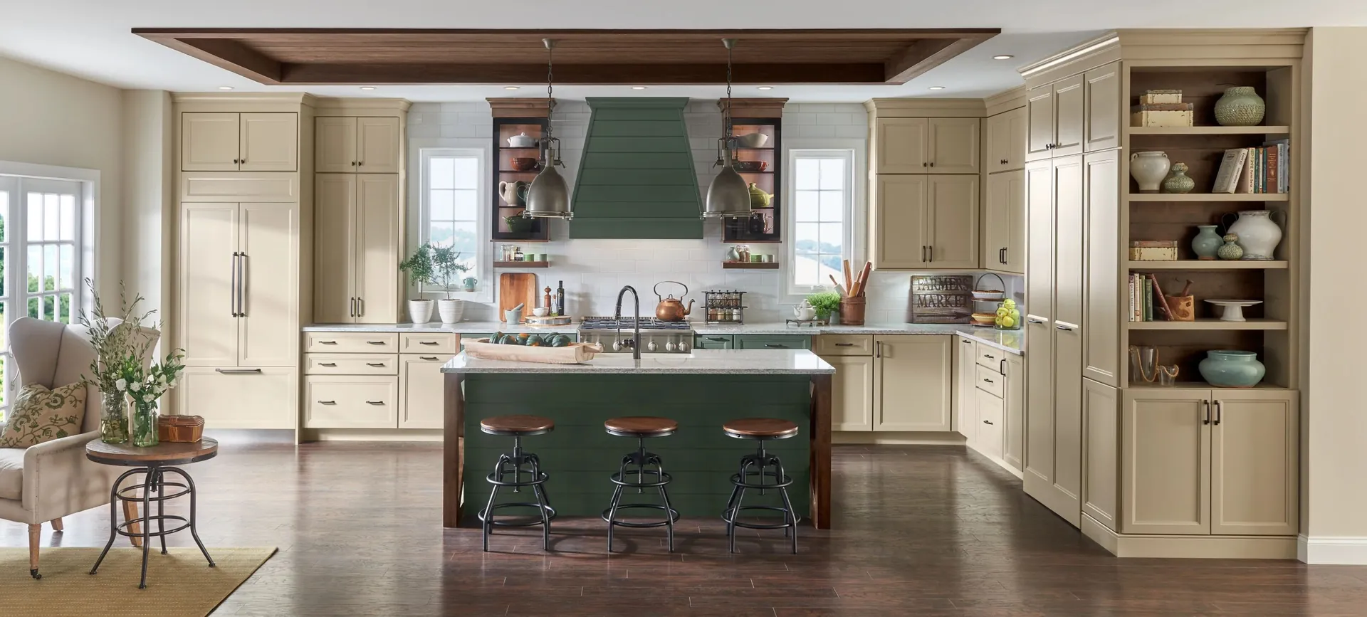 A cream kitchen with a green island and glass display cabinets, from the Medallion cabinet line we carry