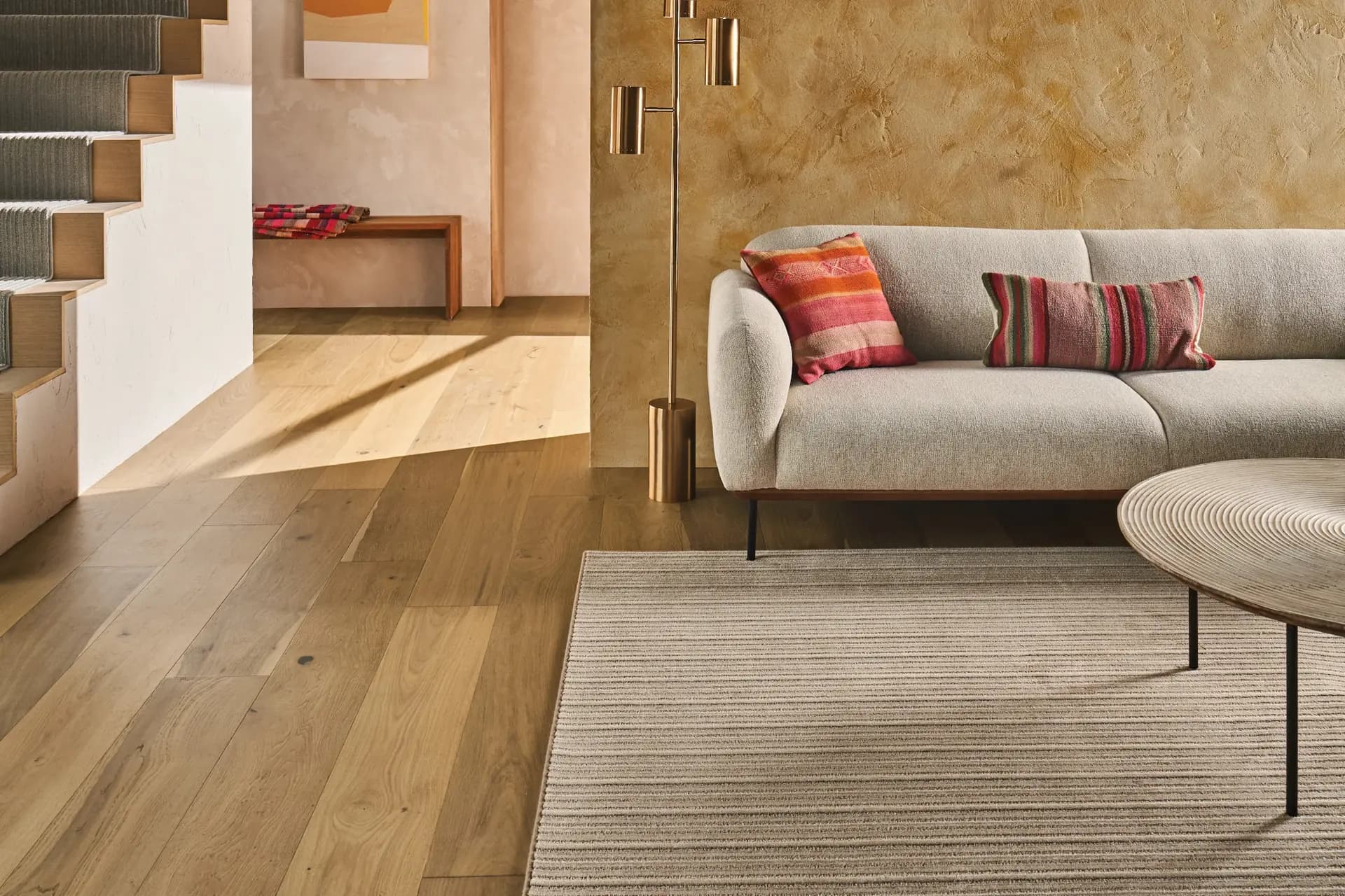Light hardwood flooring, Anderson Tuftex Natural Timbers Smooth in Orchard, in a living room with an area rug
