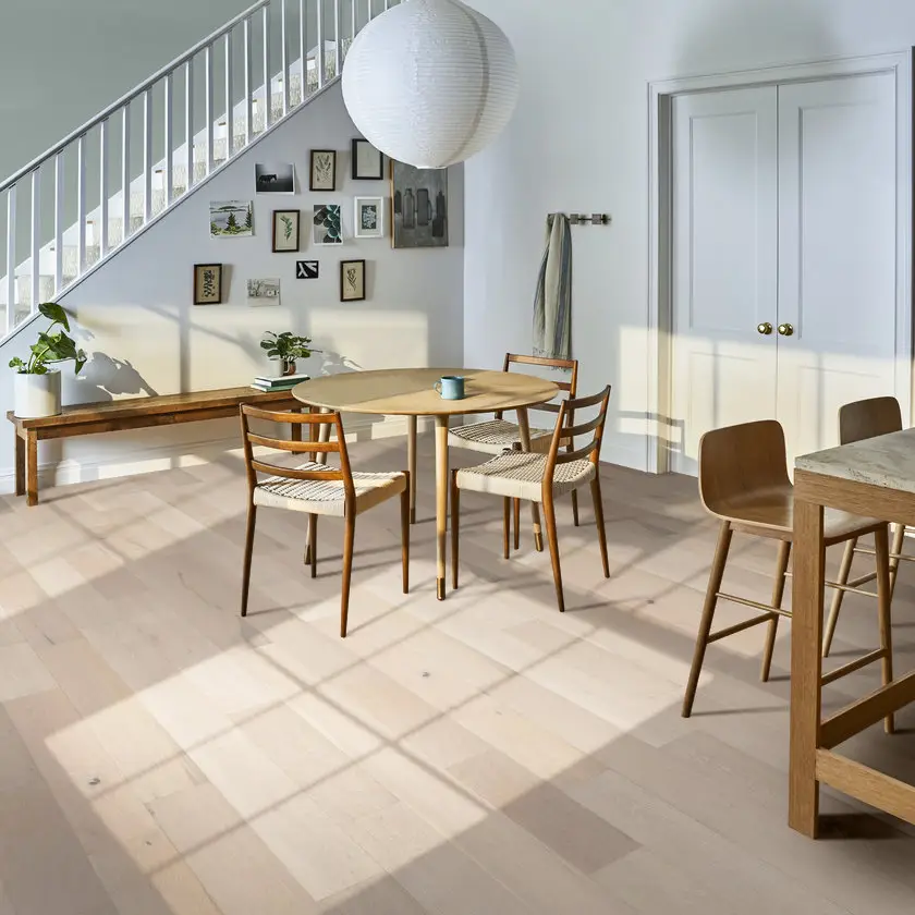Light blonde wide-plank hardwood flooring in a sunlit dining nook with mid-century chairs