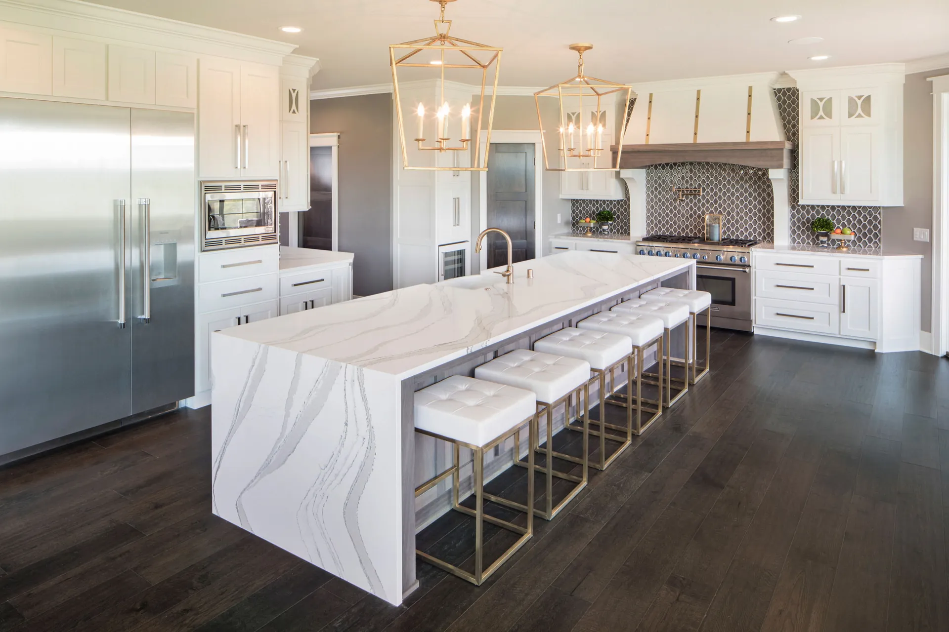 A white kitchen with a waterfall quartz island, from the Cambria quartz line we carry