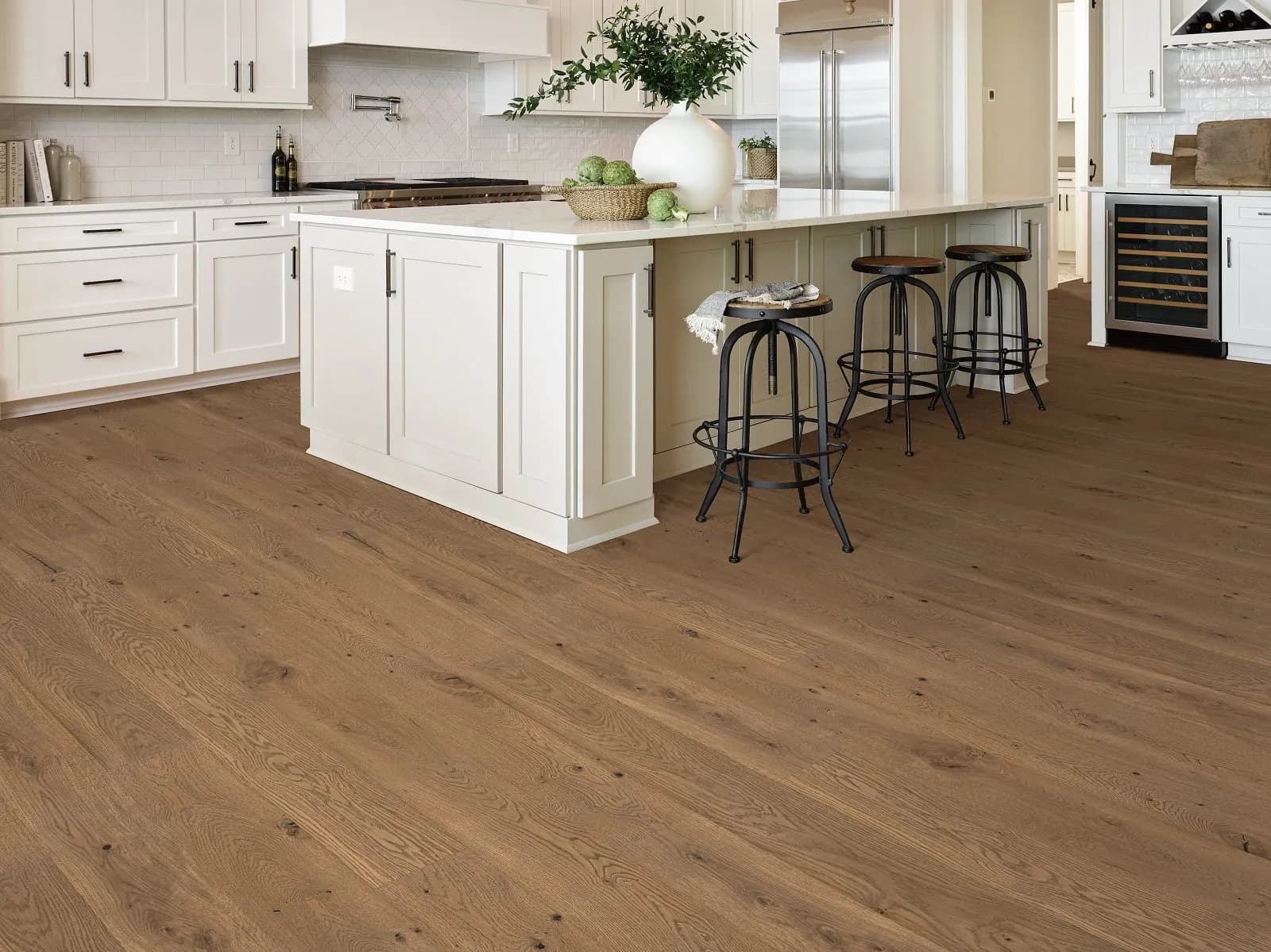 Warm dark wire-brushed white oak hardwood flooring in a white kitchen, from the Shaw hardwood line we carry