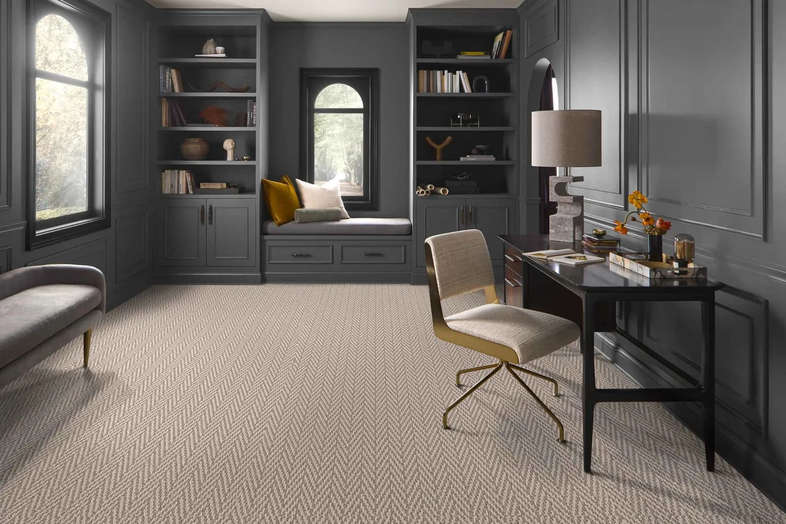 Gray patterned carpet in a moody home study with built-in shelves
