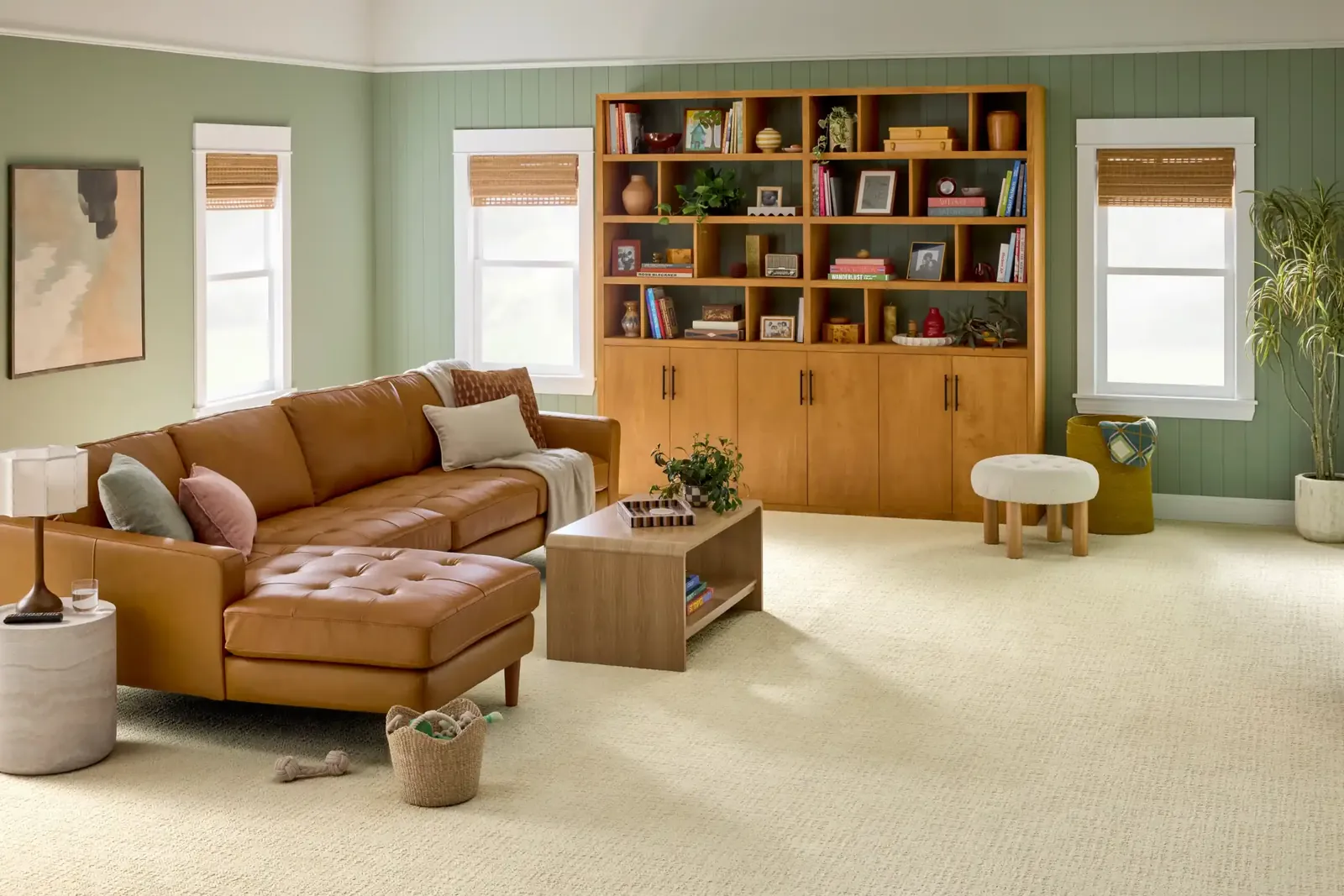 Cream textured carpet in a green living room with a caramel leather sectional