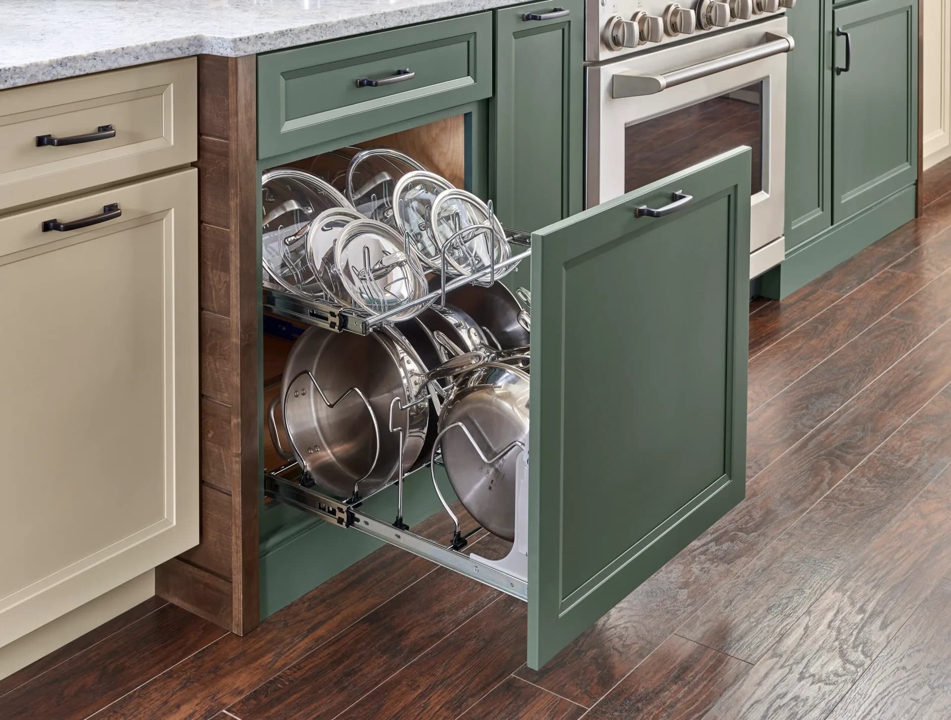 A Medallion cookware organizer pulled out of a green base cabinet, pots and lids separated in chrome racks, from the cabinet line we carry
