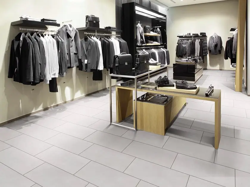 Light gray porcelain tile installed in a brick-pattern layout in a high-traffic retail menswear store