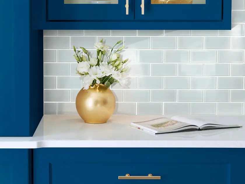 Classic white ceramic subway tile backsplash with bold blue cabinets and brass hardware