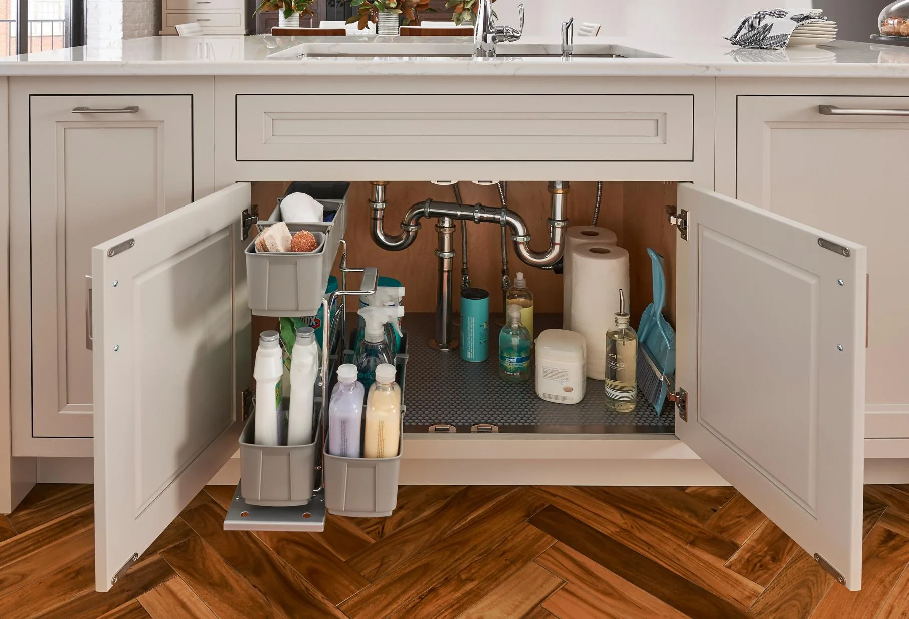 A Medallion sink-base cabinet open to the P-trap, with pull-out caddies keeping supplies clear of the plumbing, from the cabinet line we carry