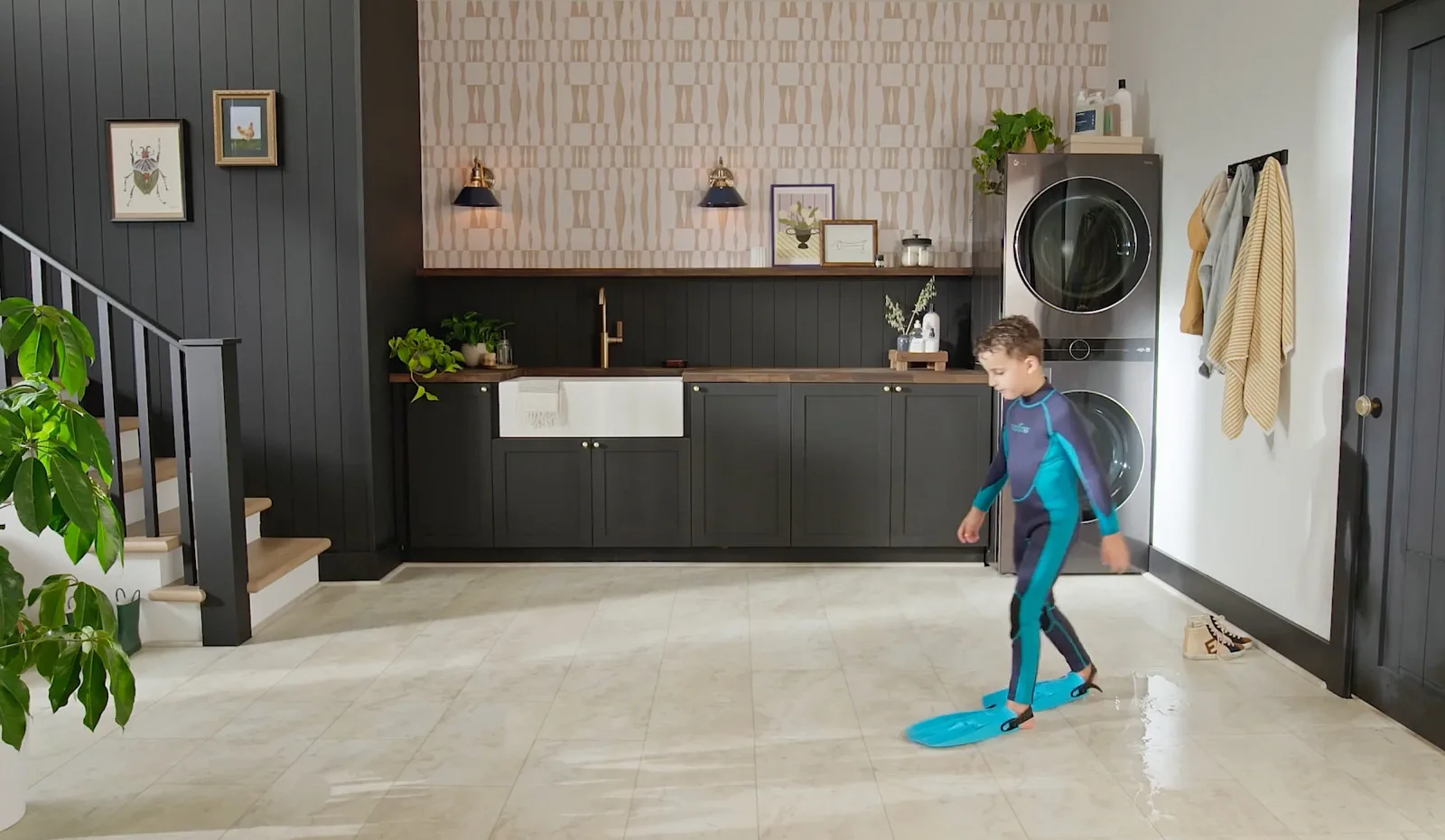 A boy in a wetsuit tracking wet footprints across waterproof COREtec vinyl flooring, a line we carry