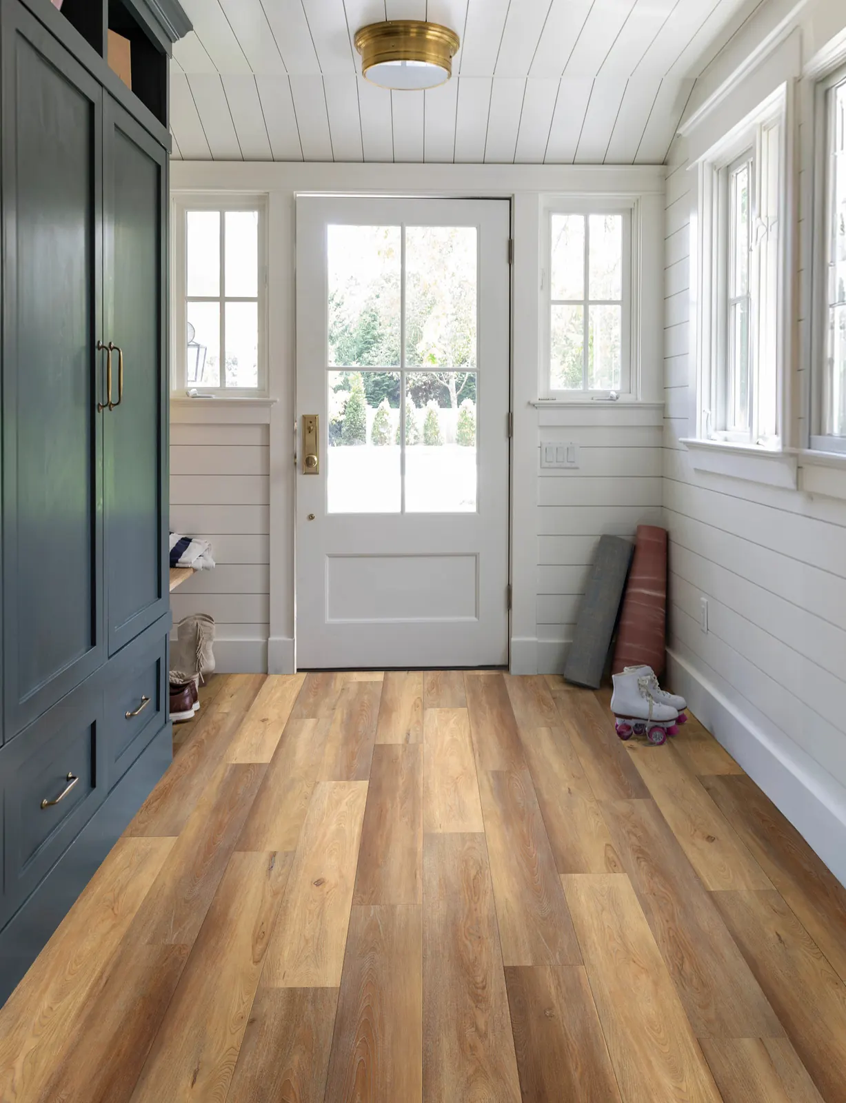 Warm wood-look vinyl planks running straight from a white front door through a shiplap entry