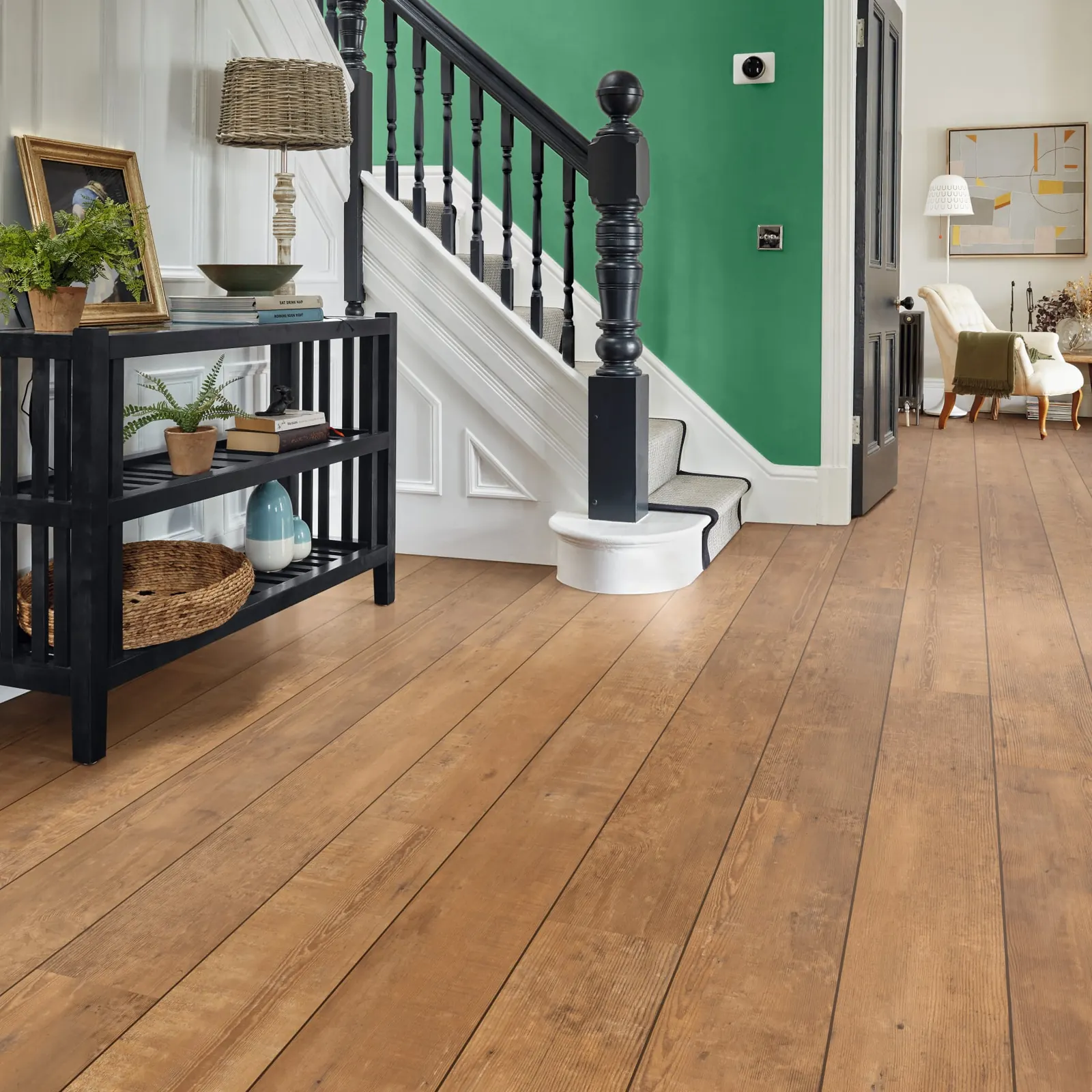 Wide wood-look planks running past a staircase and on through a doorway into the next room