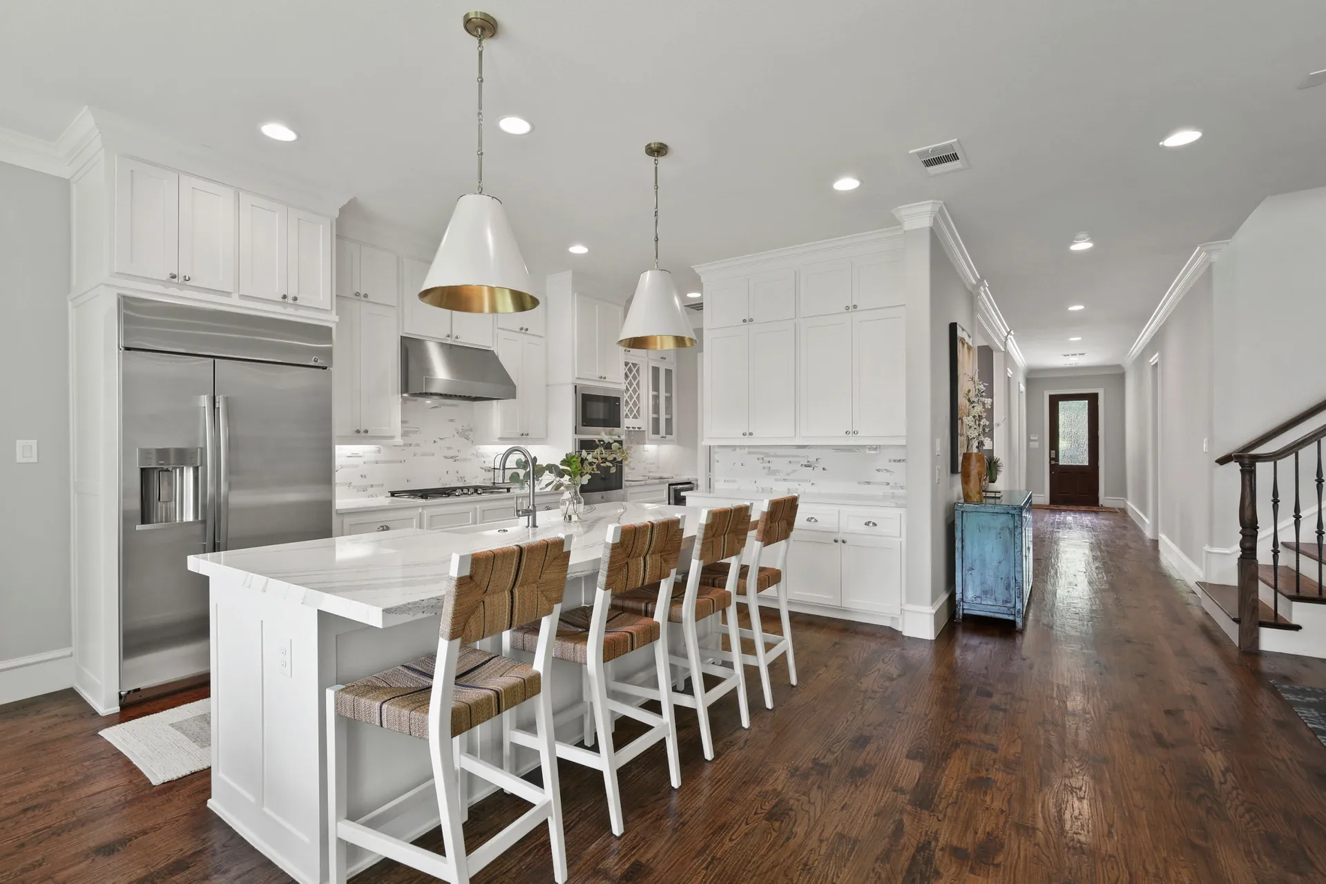 A white kitchen with a marble-look quartz island, from the Cambria quartz line we carry