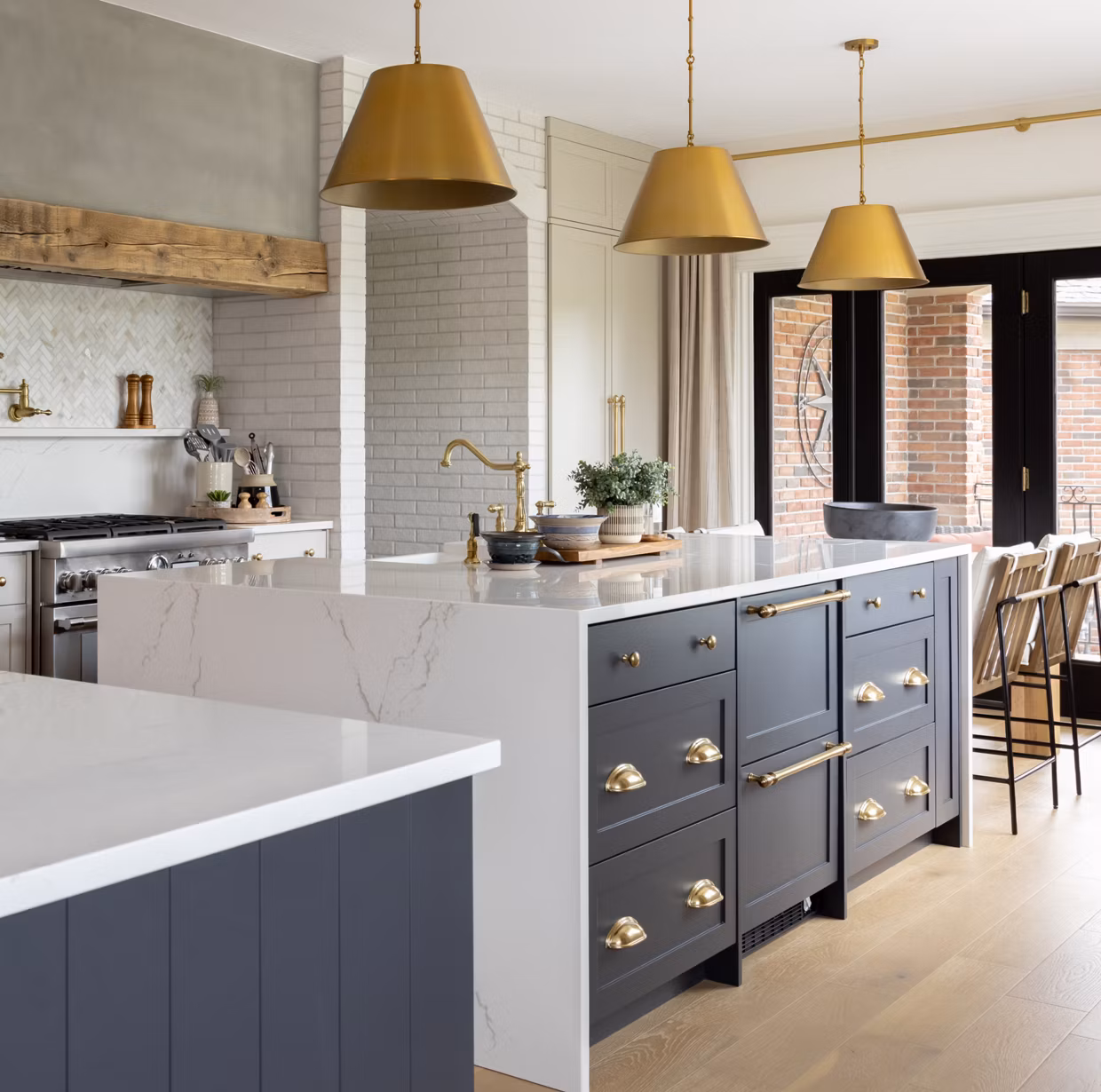 Navy shaker kitchen cabinets with brass hardware and a white waterfall island, one of the cabinet looks Blackburn's Interiors offers Lake Wales, FL homeowners, family-owned since 1962