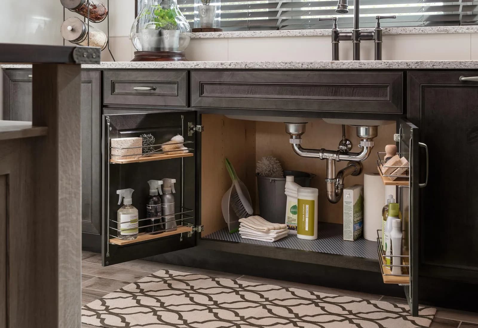 A Medallion sink base open to a protective mat, door organizers, and pull-out storage around the plumbing