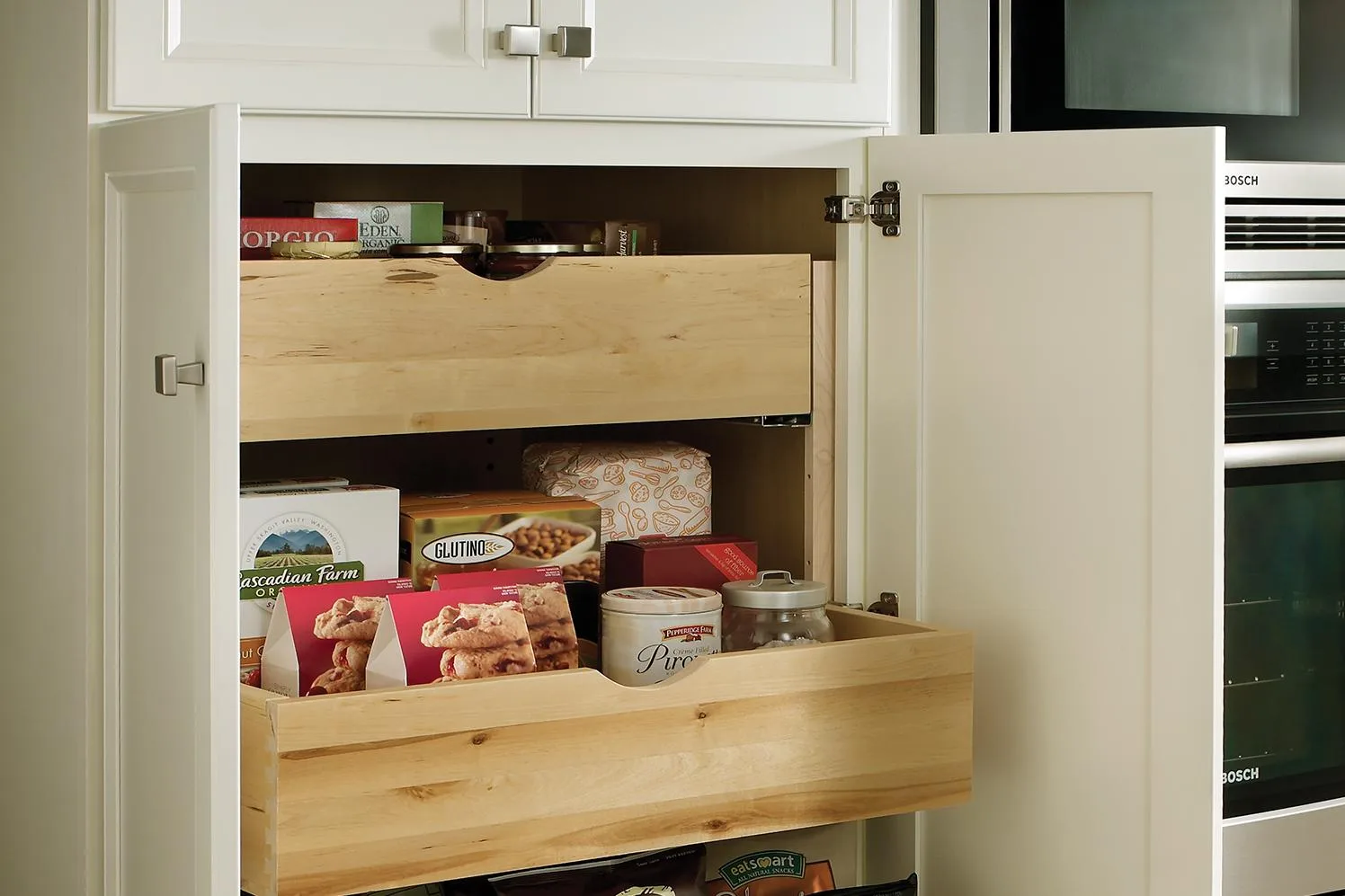 A Medallion tall pantry cabinet with deep roll-out trays pulled forward, loaded with pantry goods