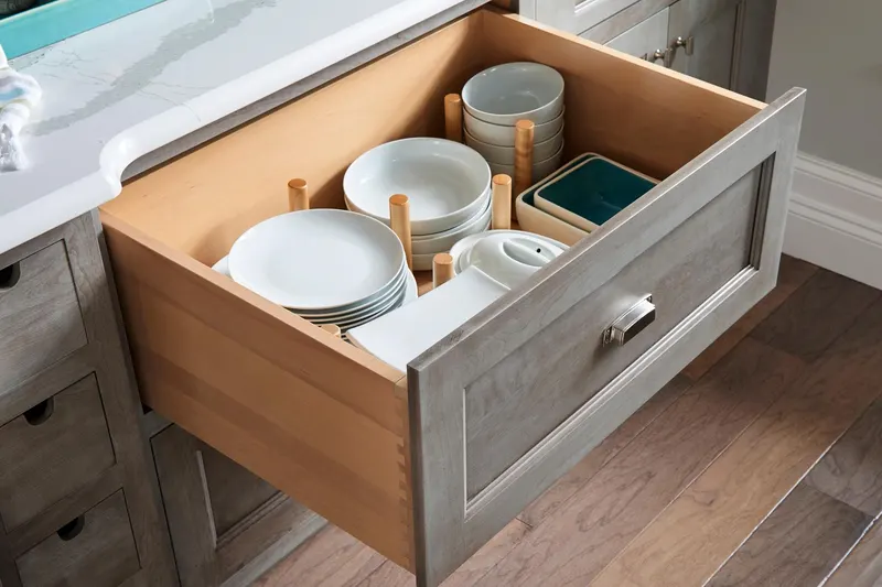 A deep Medallion drawer with movable wooden pegs holding plates and bowls in place