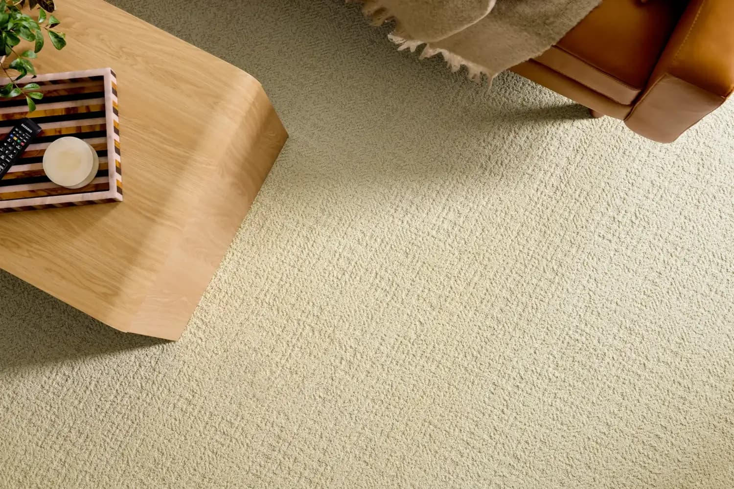 Shaw Floors Tailored Craft carpet in Oxford, an ivory patterned loop, in a living room with a light wood coffee table and a leather seat.