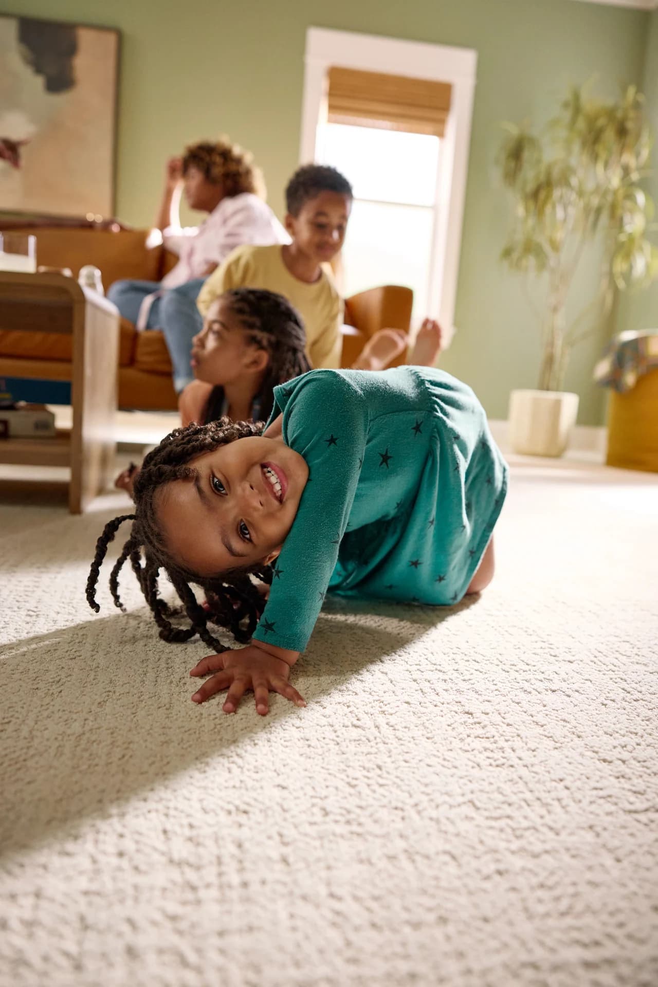 Children playing on Shaw Tailored Craft carpet in Oxford in a sage green living room. Carpet for Lakeland, FL homes