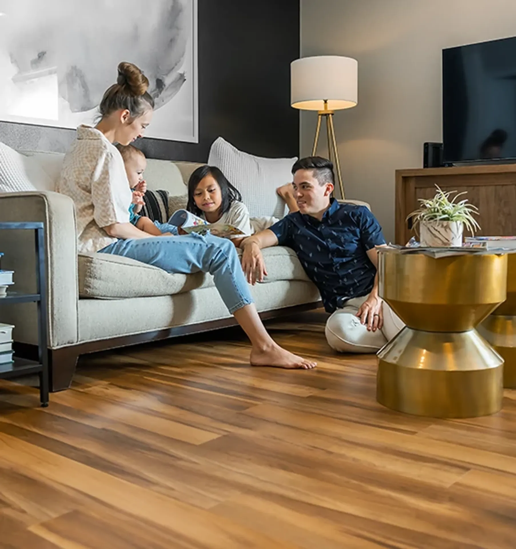 Family on a sofa over COREtec luxury vinyl plank in a living room. Carried by Blackburn's Interiors, Winter Haven, FL