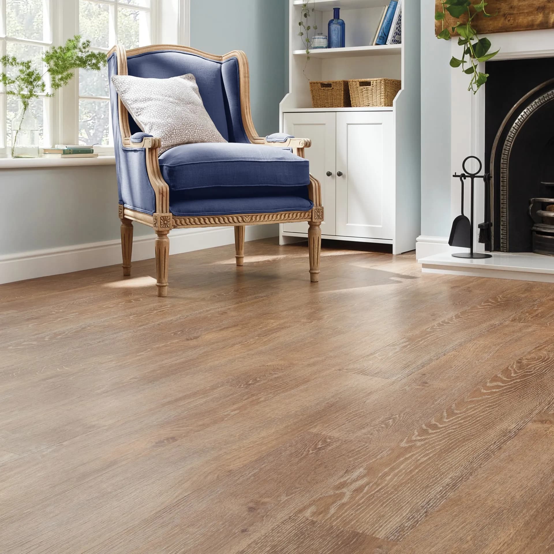 Karndean luxury vinyl plank beside a fireplace and a blue armchair. Carried by Blackburn's Interiors, Winter Haven, FL