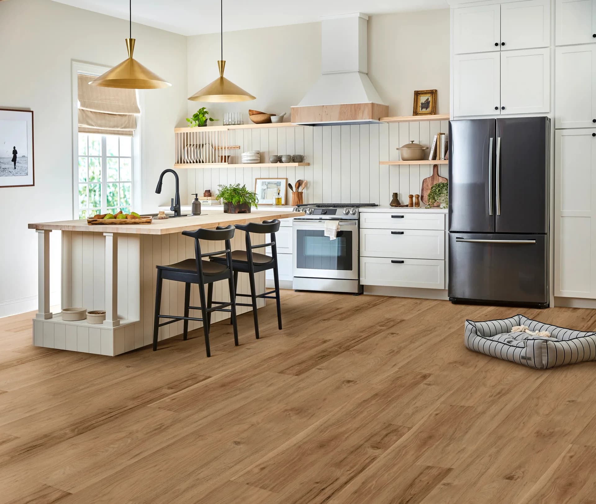 Shaw Ignite luxury vinyl plank in Torchwood in a bright white kitchen with a wood-topped island. Luxury vinyl plank for Auburndale, FL homes