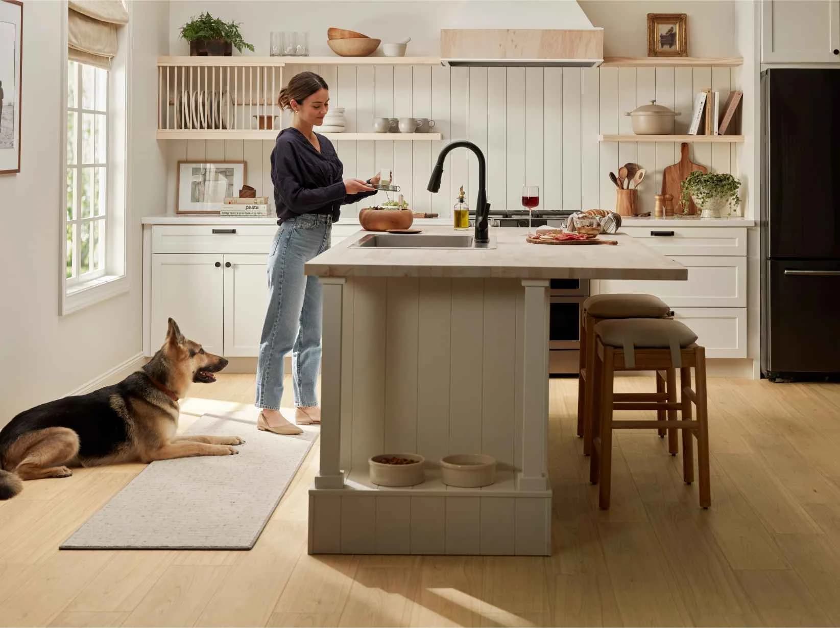 Shaw Cattitude luxury vinyl plank in Hygge in a white kitchen, with a dog resting by the island. Luxury vinyl plank for Lake Alfred, FL homes