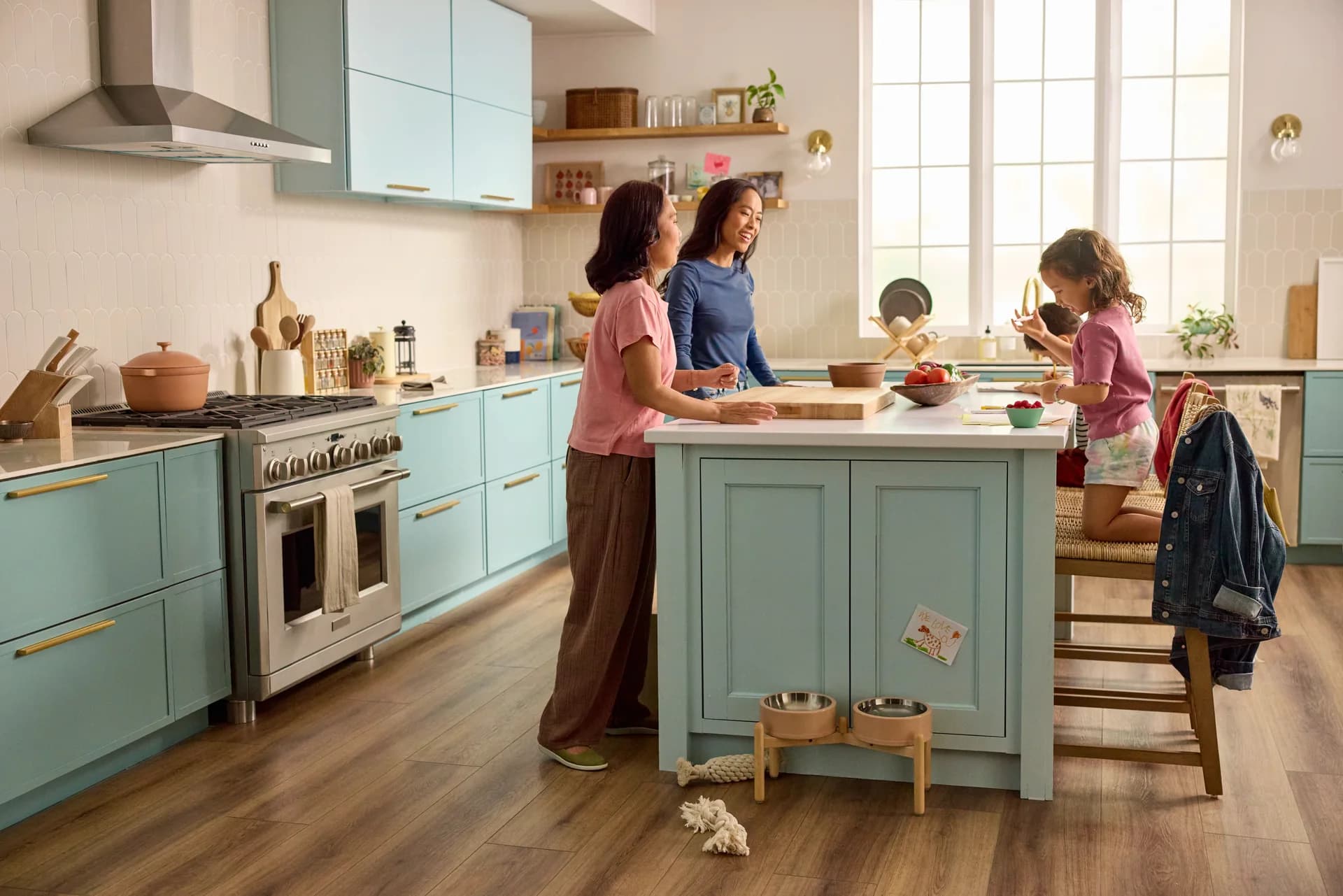 Shaw Pet Perfect luxury vinyl plank in Coffee Oak in a family kitchen with a blue island and pet bowls. Luxury vinyl plank for Lake Wales, FL homes