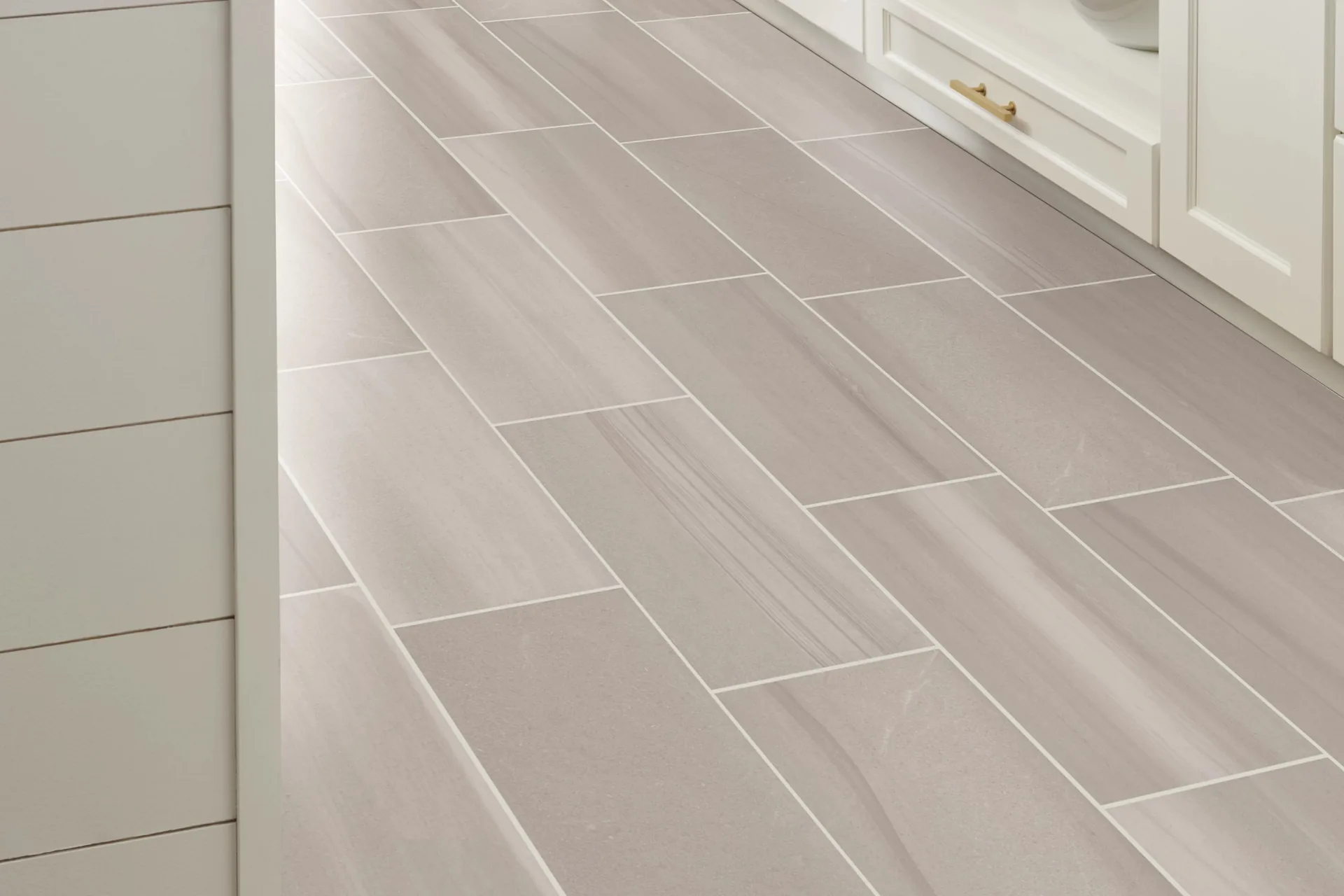 Light stone-look 12x24 floor tile beside white cabinetry — waterproof bathroom flooring, Winter Haven, FL