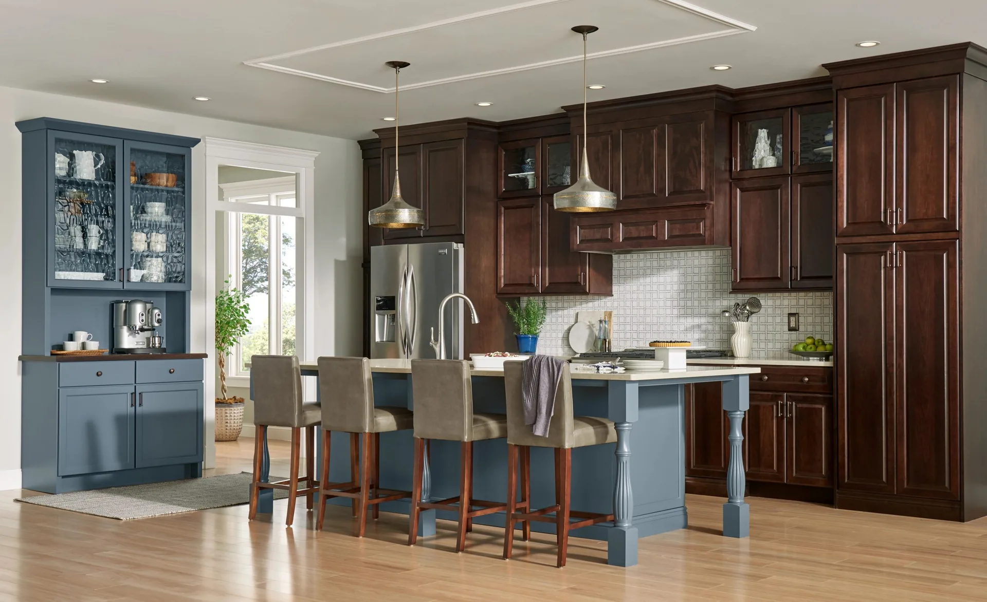 Kitchen with dark-stained Medallion Jackson raised panel cabinets around the perimeter and a slate blue painted island with seating, from the Medallion line we sell and install