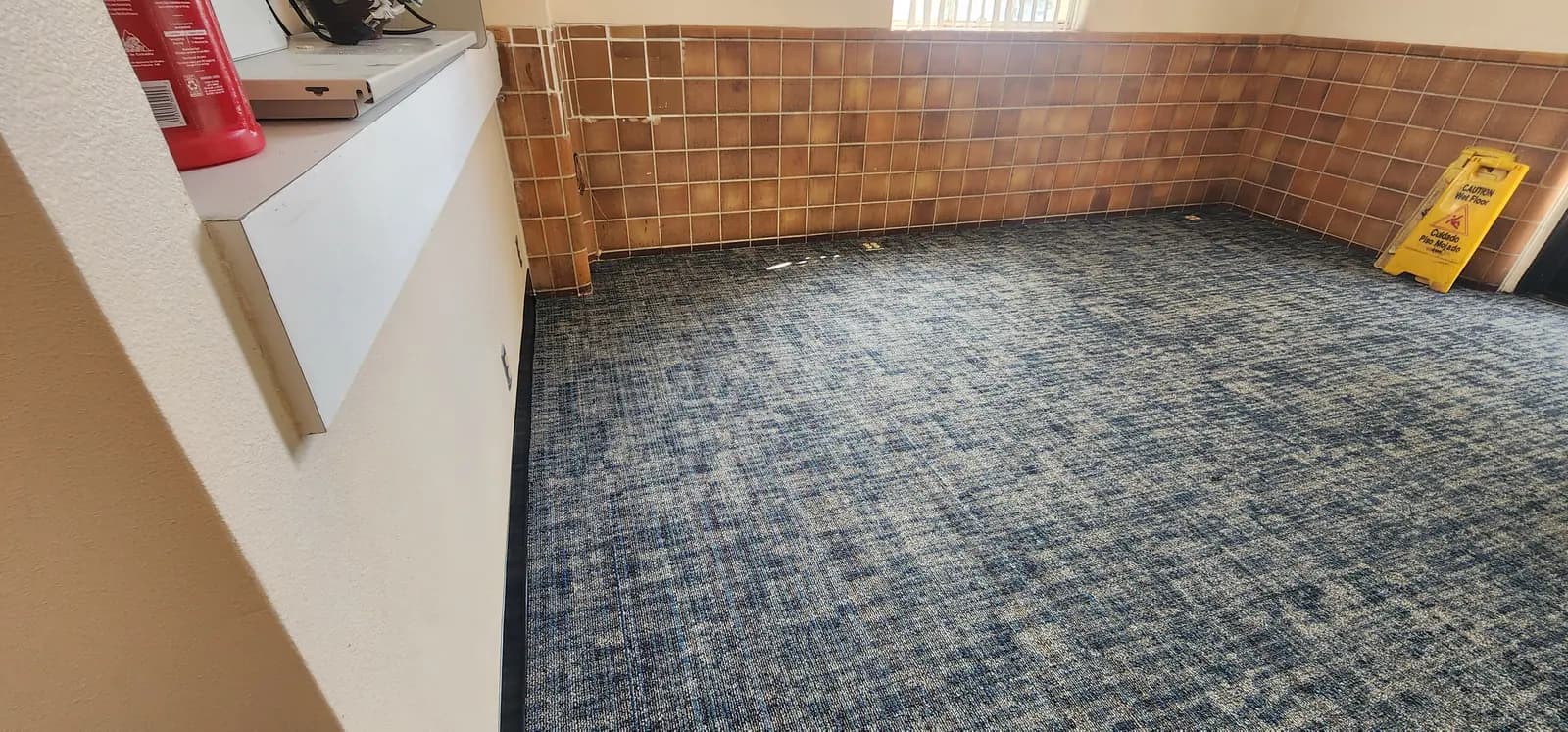 New blue-gray Terrena carpet tile and black cove base meeting the glazed block wall inside the Federal Building entry