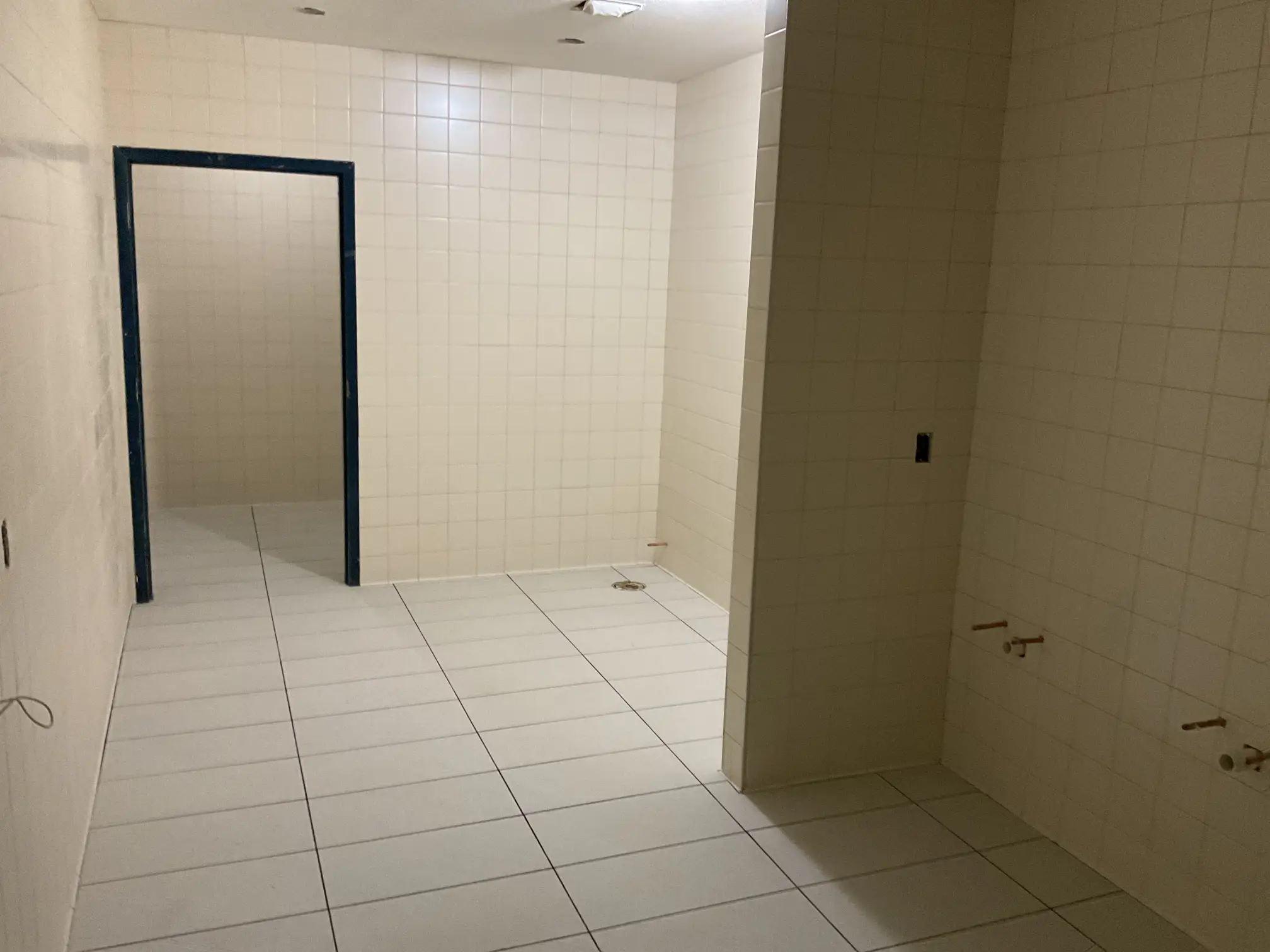 White floor and wall tile with a floor drain in a restroom at the DeSoto County Admin Building