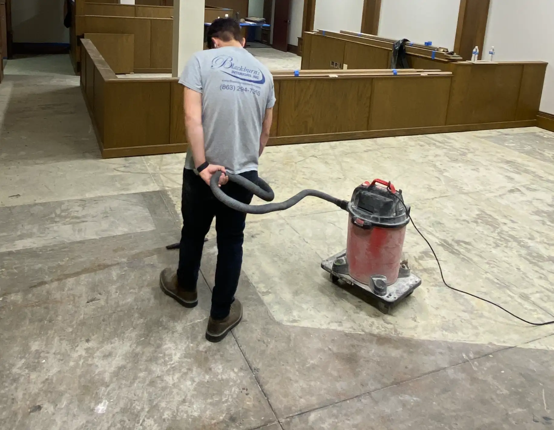 Vacuuming the bare concrete subfloor in a DeSoto County Courthouse courtroom before the new carpet tile goes down