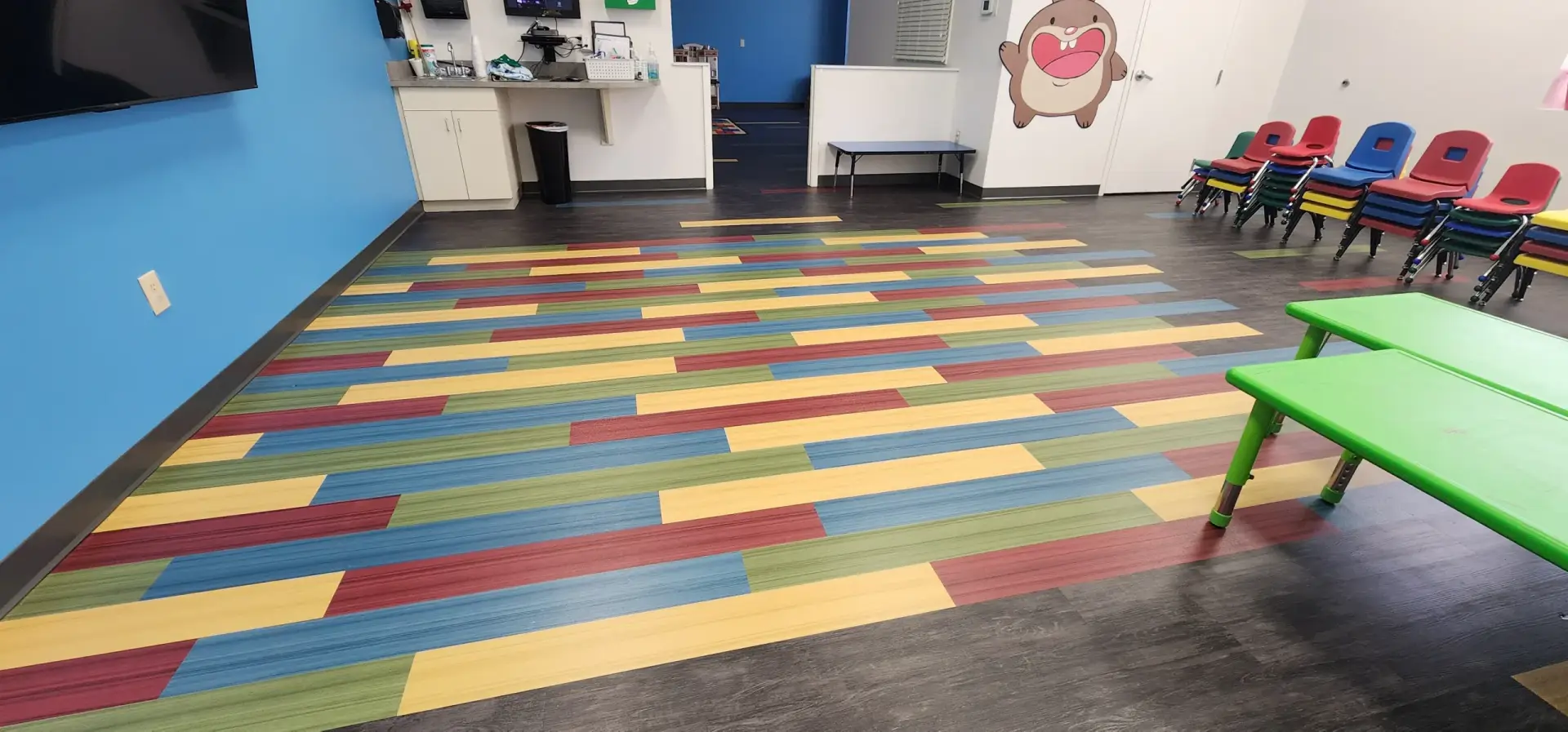 Heartland Church Kids Area in Winter Haven, FL with the dark wood-look LVP floor and the red, yellow, blue, and green accent rectangle that marks the gathering zone