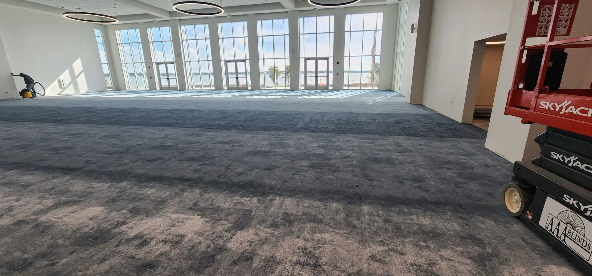 Main event hall at Lake Ariana Civic Center with dark blue Tarkett carpet tile installed and lake views through the front windows