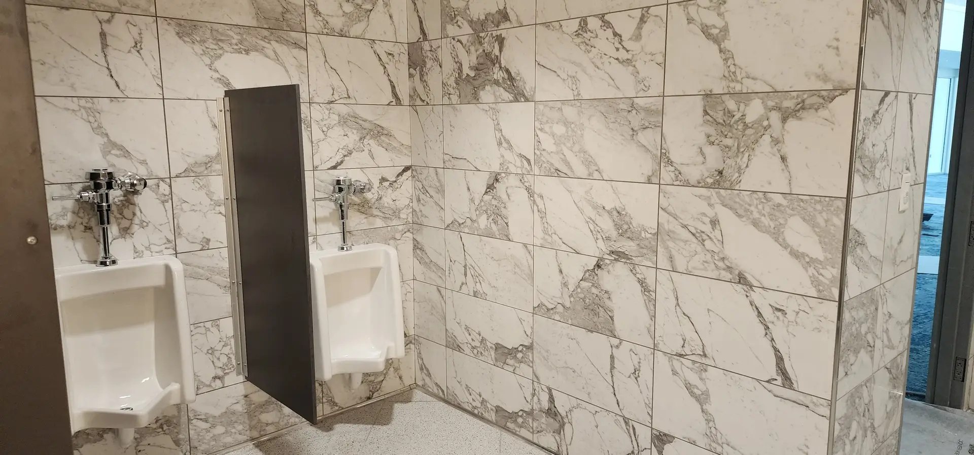 Marble-look porcelain wall tile behind the urinal wall in the Lake Ariana Civic Center men's restroom
