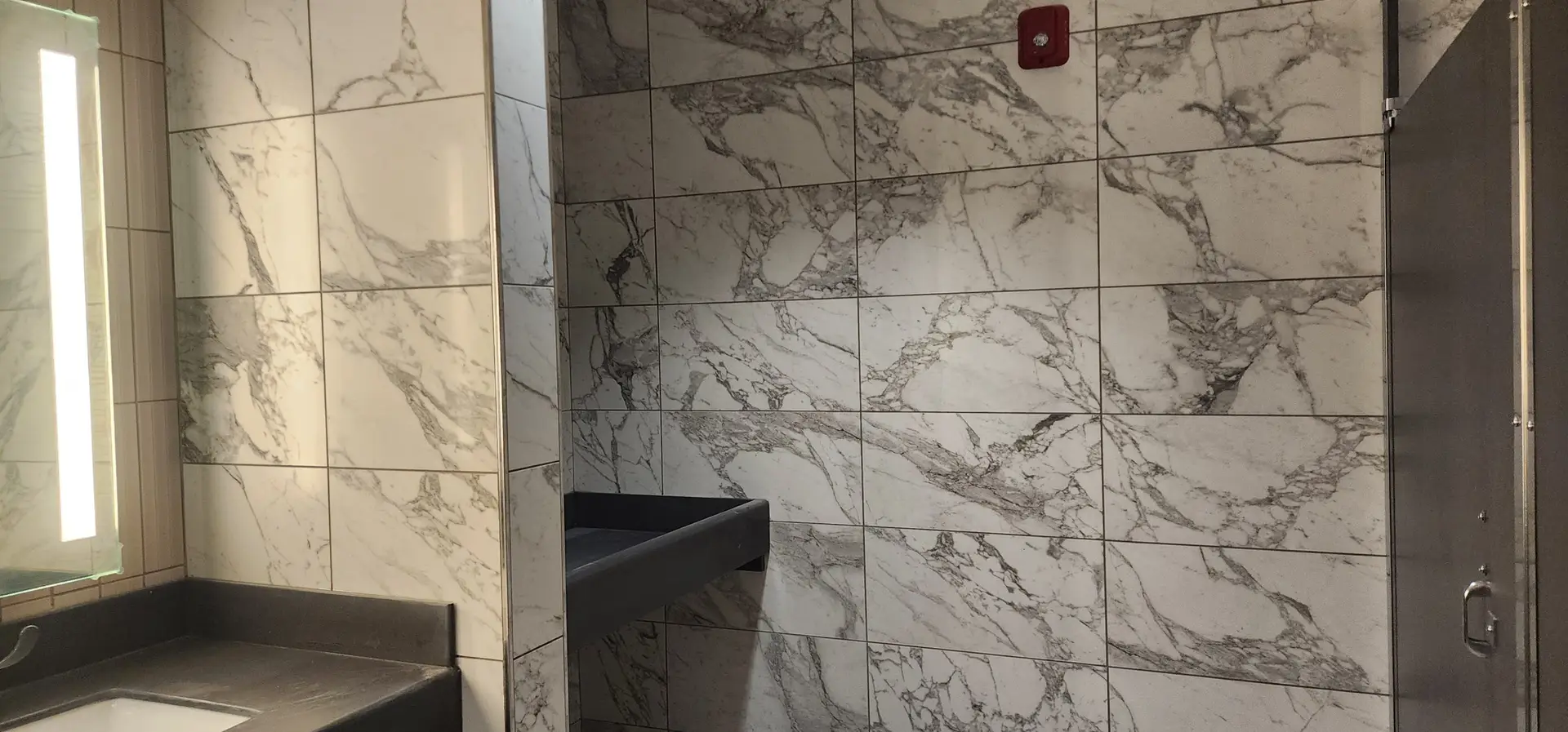Close-up of the white marble-look porcelain wall tile and gray countertop installed in the civic center restroom