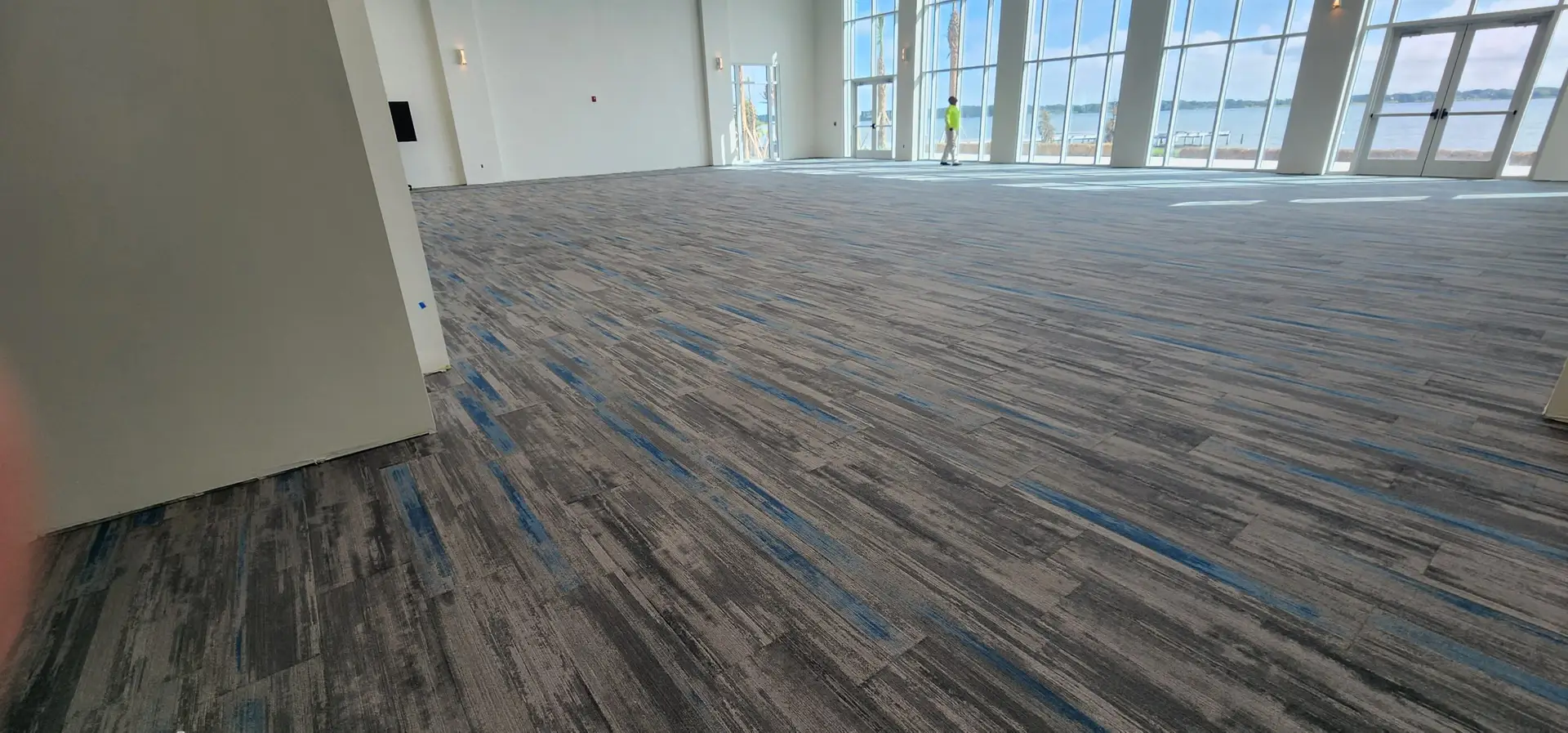 Patterned luxury vinyl plank running through the main hall of Lake Ariana Civic Center in Auburndale, FL with floor-to-ceiling lakefront windows
