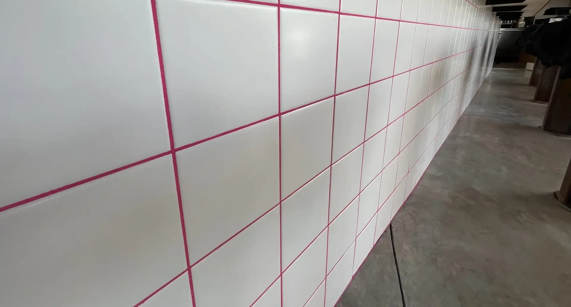 Detail of glossy white square wall tile with bright pink grout joints running down the bar wall at LoveBird Chicken