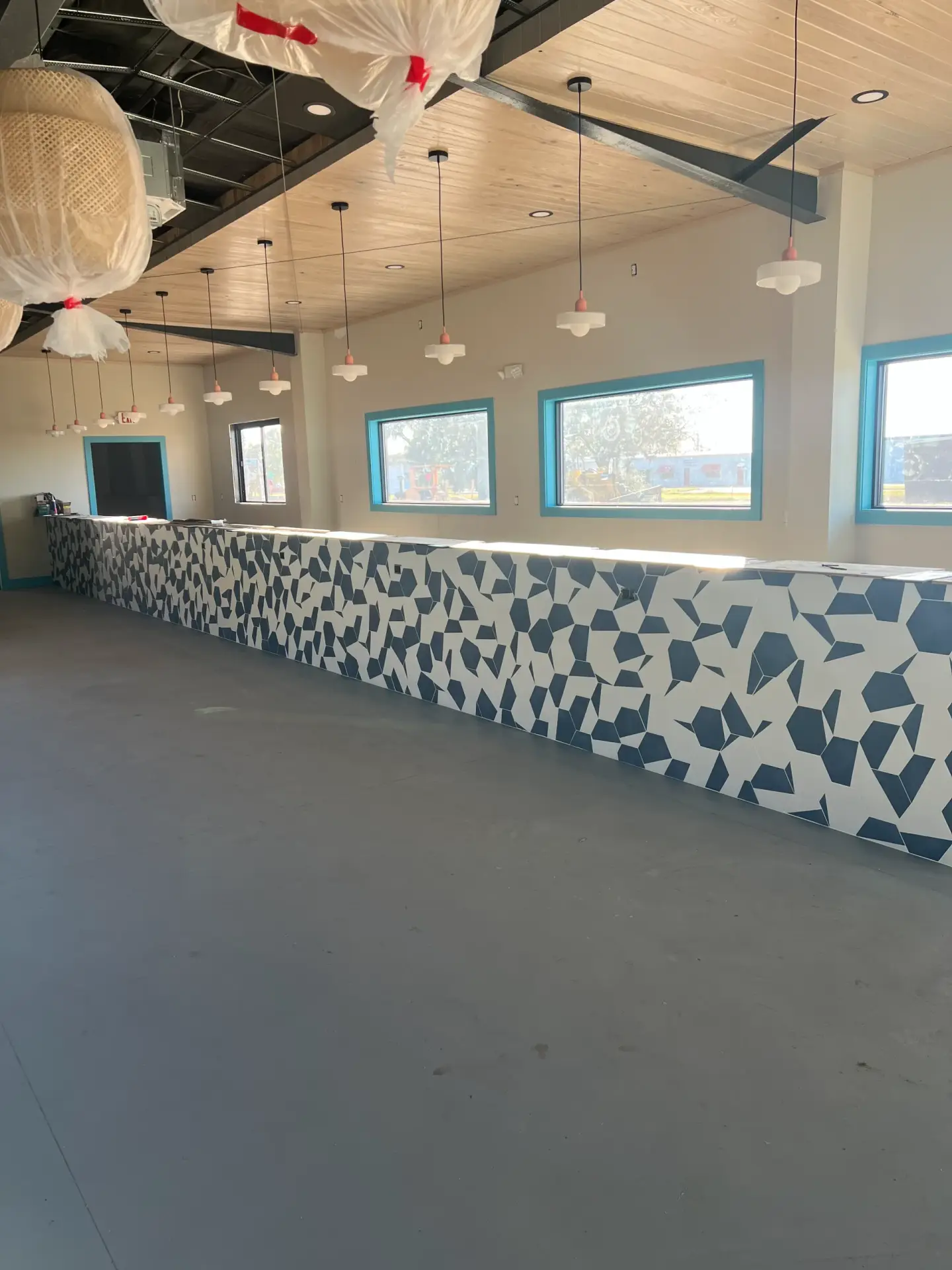 Wide view down the full length of the new tile-wrapped bar at Maritime Winter Haven with wood plank ceiling and pendant lighting