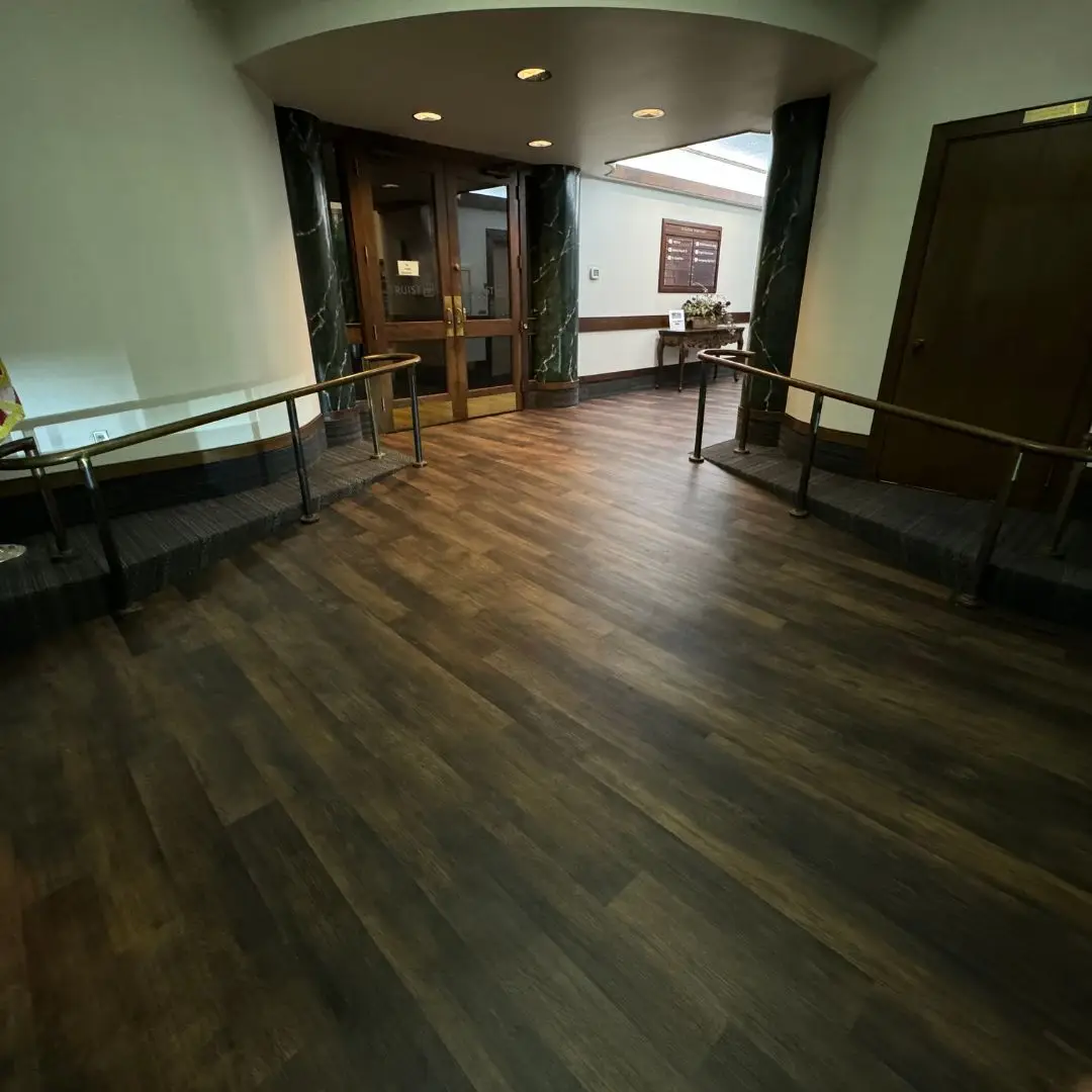 Munn Park Building lobby in Lakeland showing the new dark LVP floor leading to the Truist Bank doors between green marble columns