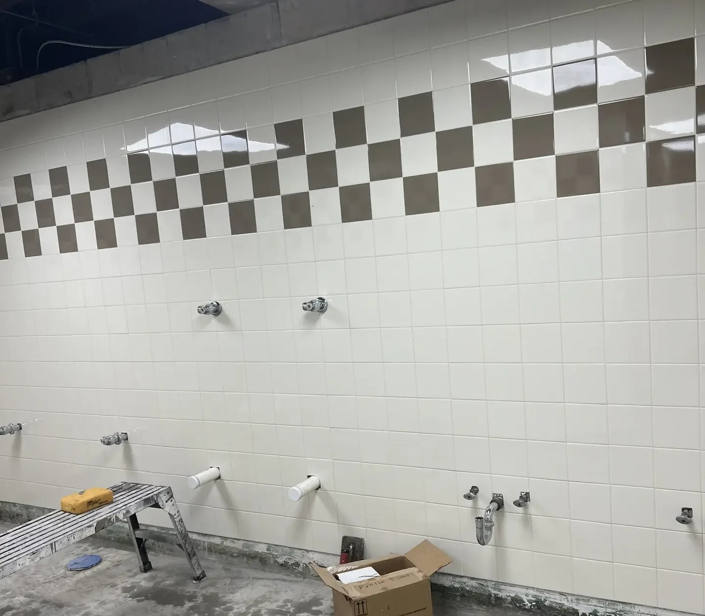 White 6-inch Daltile wall tile installed 8 feet high with a tan checkerboard accent course at the Publix Fleet Maintenance restroom in Lakeland, FL