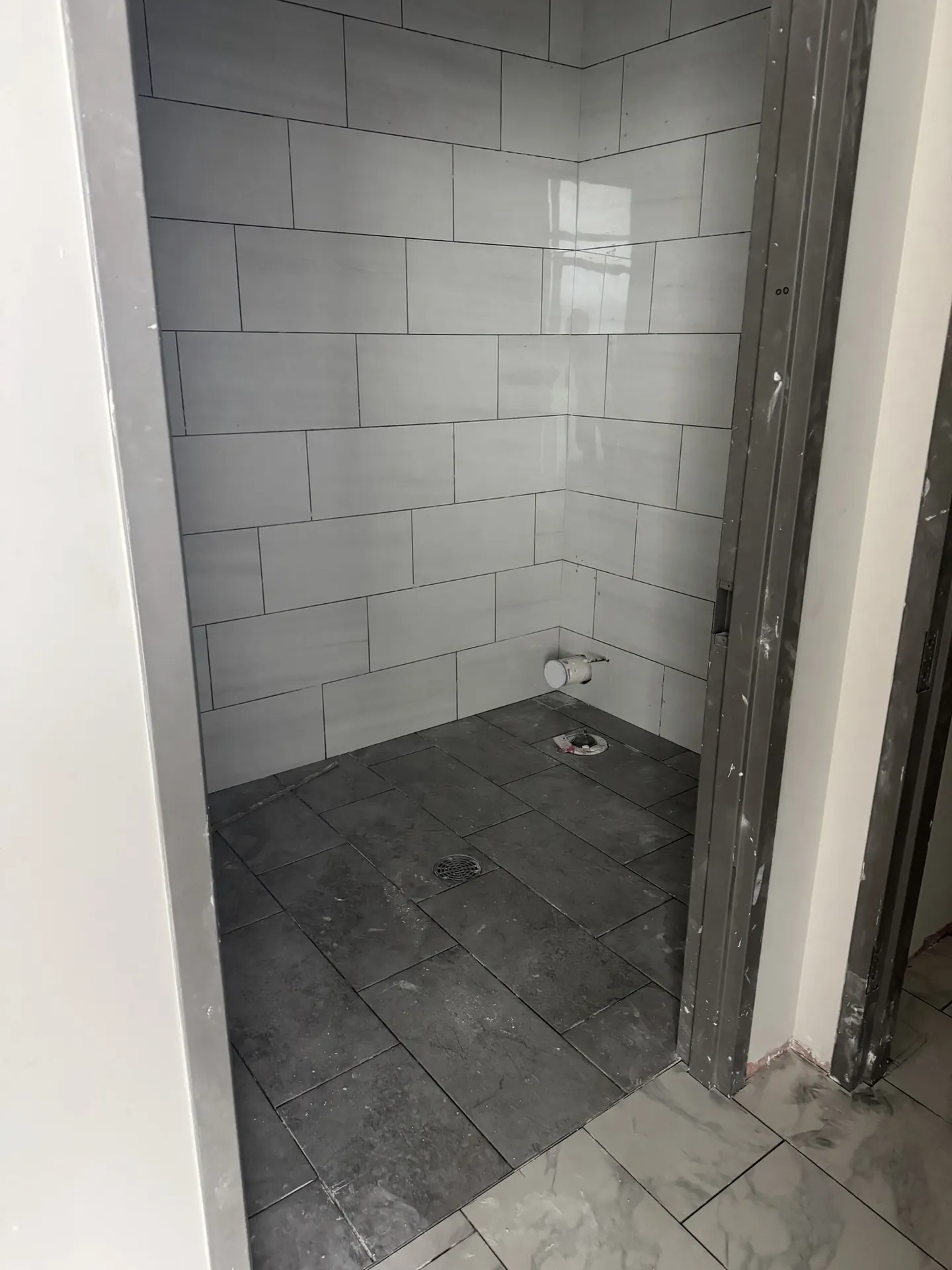 Office restroom stall at Sand Lake Vista with white marble-look wall tile and gray Daltile StepWise floor tile around the floor drain