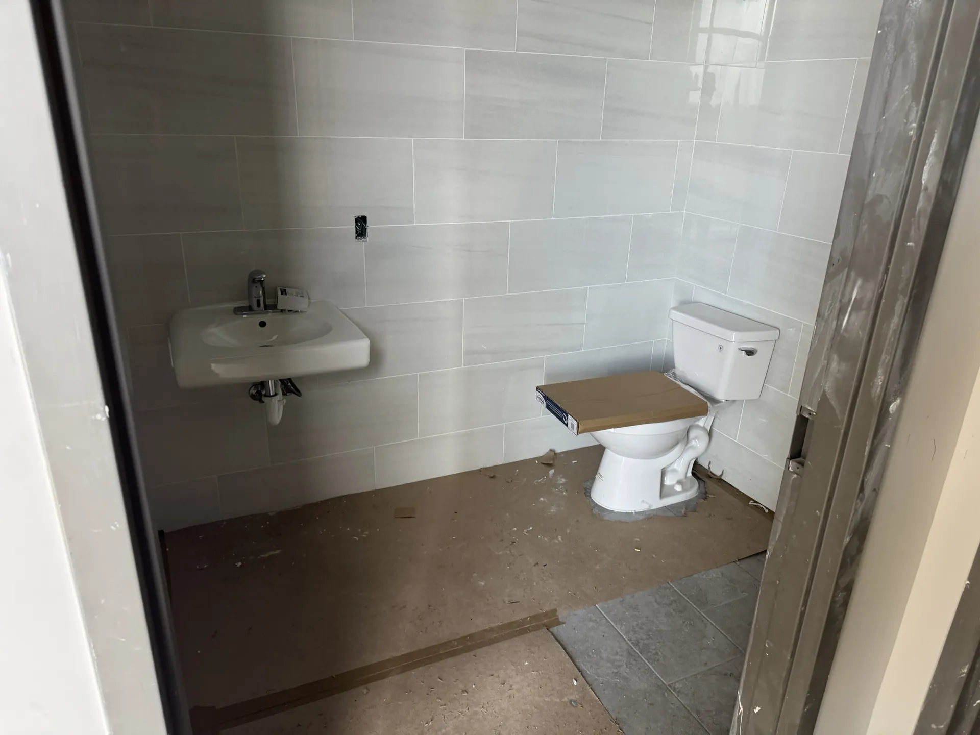 Sand Lake Vista restroom with the marble-look wall tile complete and the gray floor tile starting at the doorway
