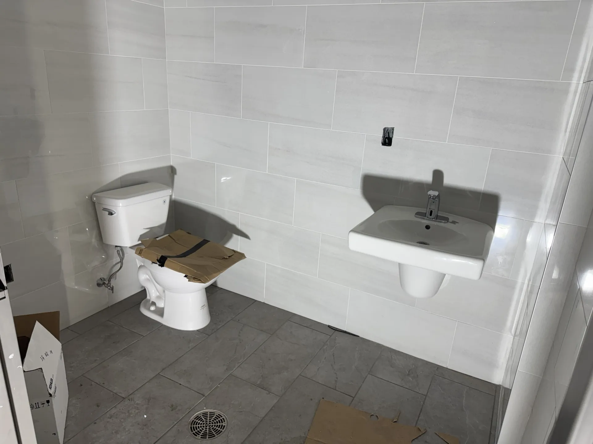 Wall-hung sink and toilet against 12x24 marble-look porcelain wall tile in a finished Sand Lake Vista office restroom